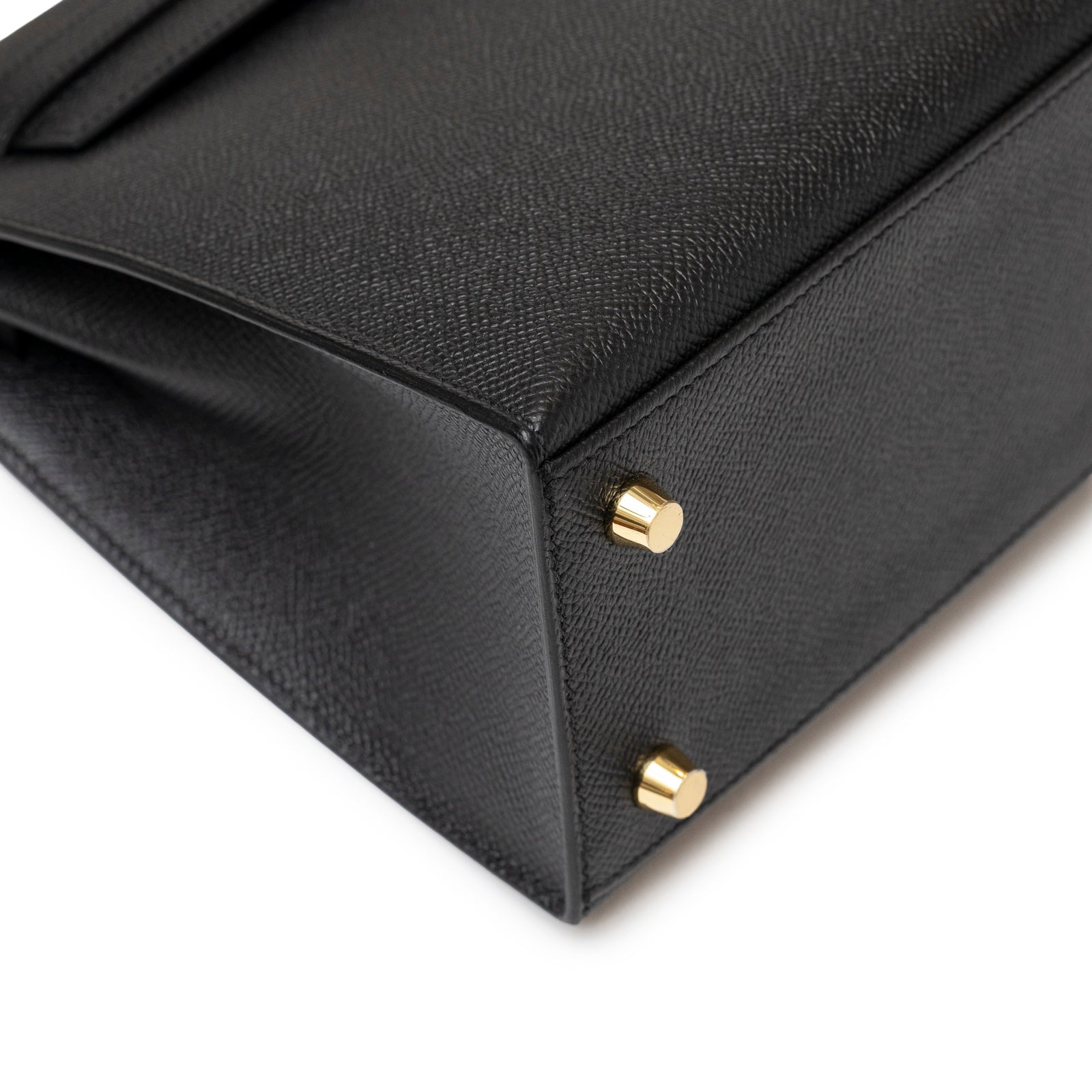 Close-up of Hermès Kelly 25 Sellier Black Epsom Gold hardware showcasing textured leather and polished gold feet details