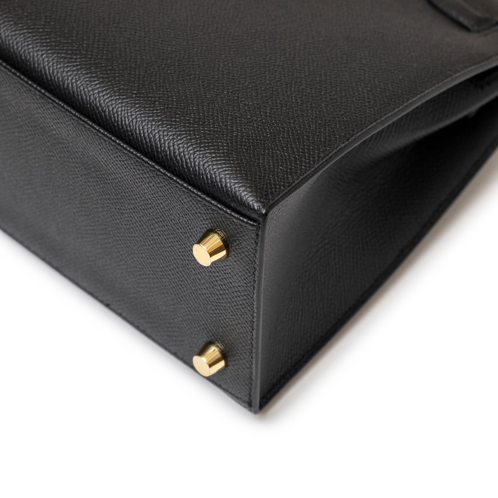 Close-up of the Hermès Kelly 25 Sellier Black Epsom Gold hardware showing textured leather and protective gold metal feet.