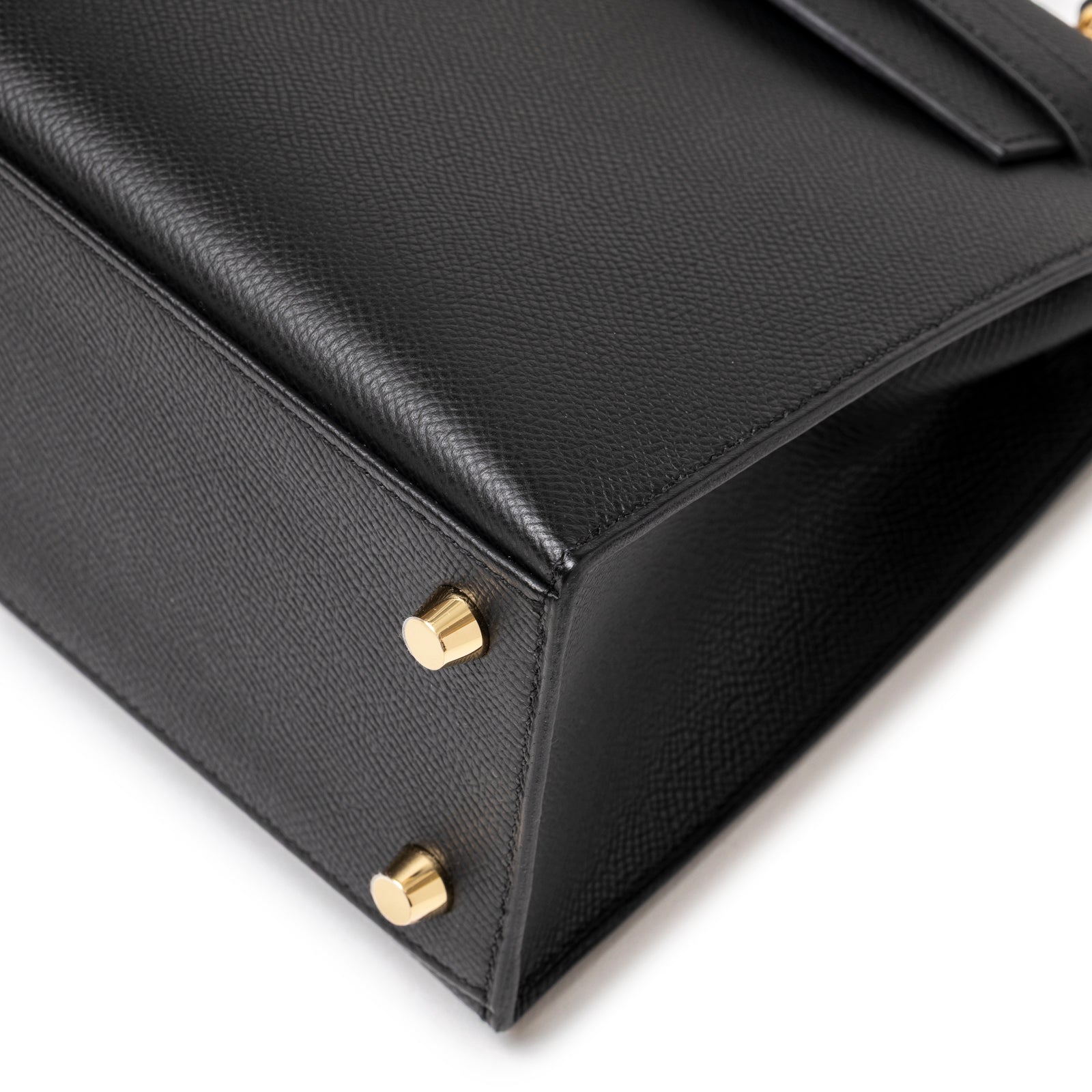 Close-up of gold feet and textured black leather corner on Hermès Kelly 25 Sellier Black Epsom Gold Hardware handbag