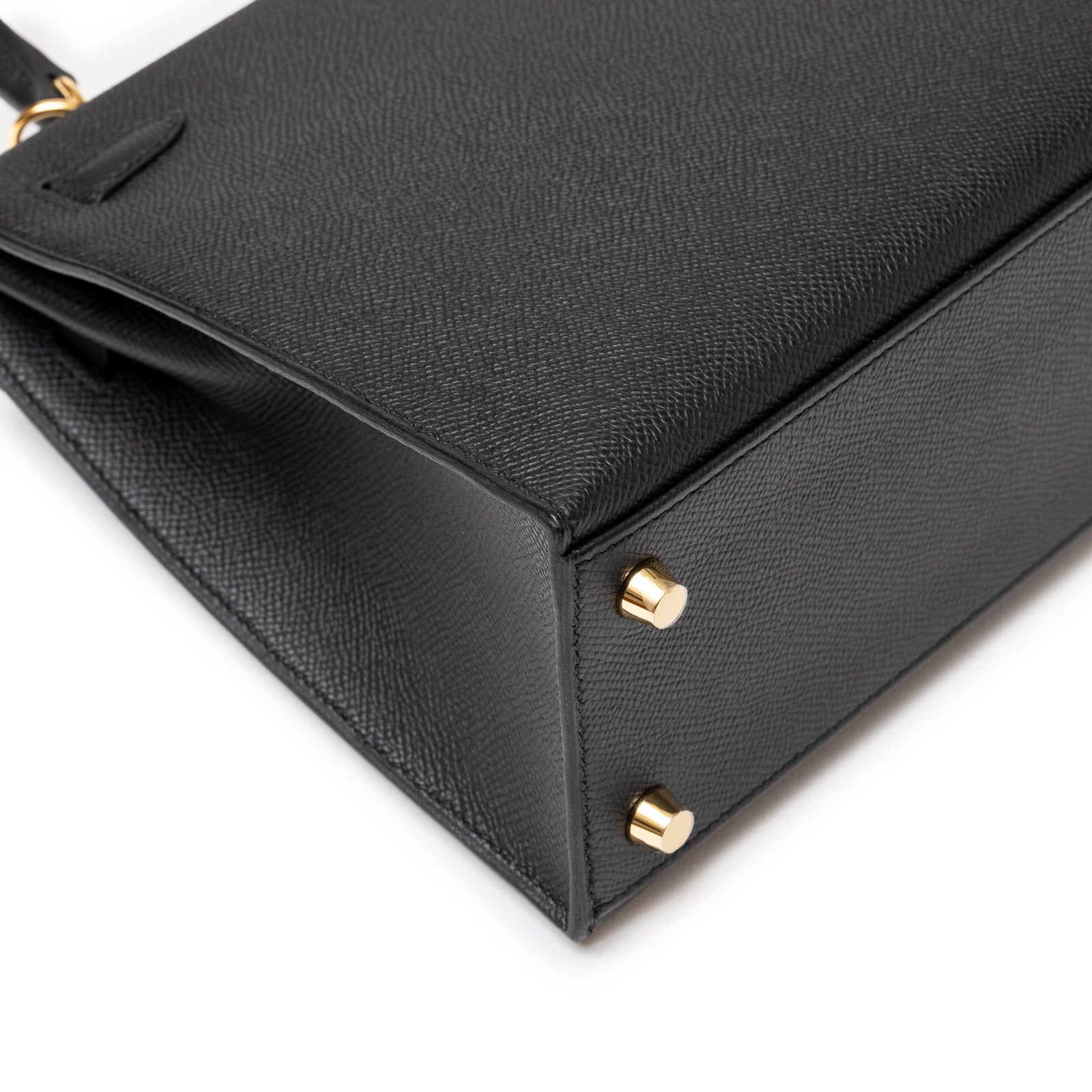 Close-up of base corner showing gold feet and textured leather on Hermès Kelly 25 Sellier Black Epsom Gold Hardware