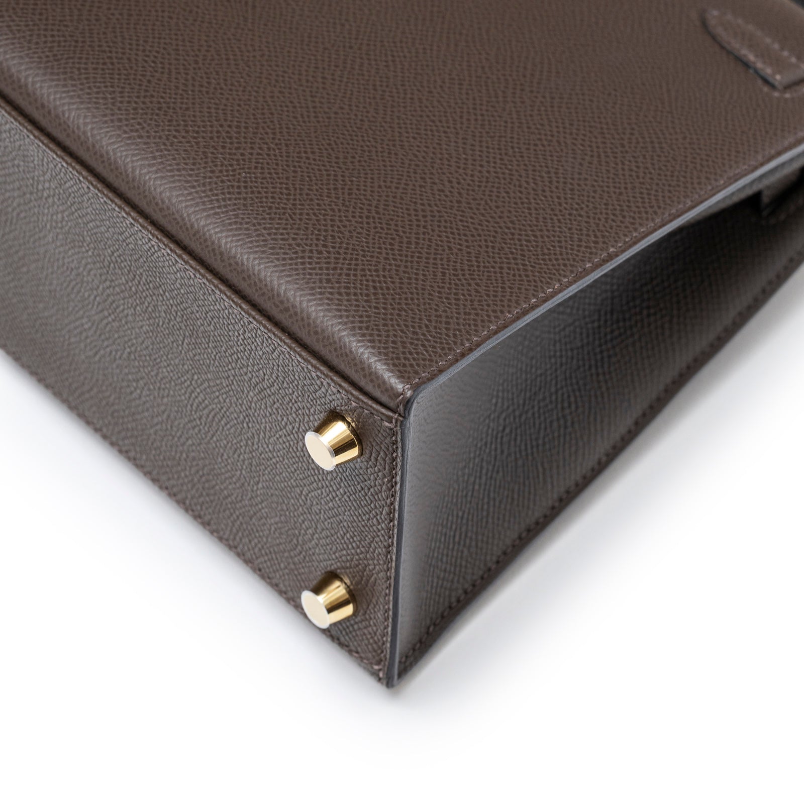 Close-up of base corner showing gold hardware feet on Hermès Kelly 25 Sellier Ecore Epsom Gold Hardware bag