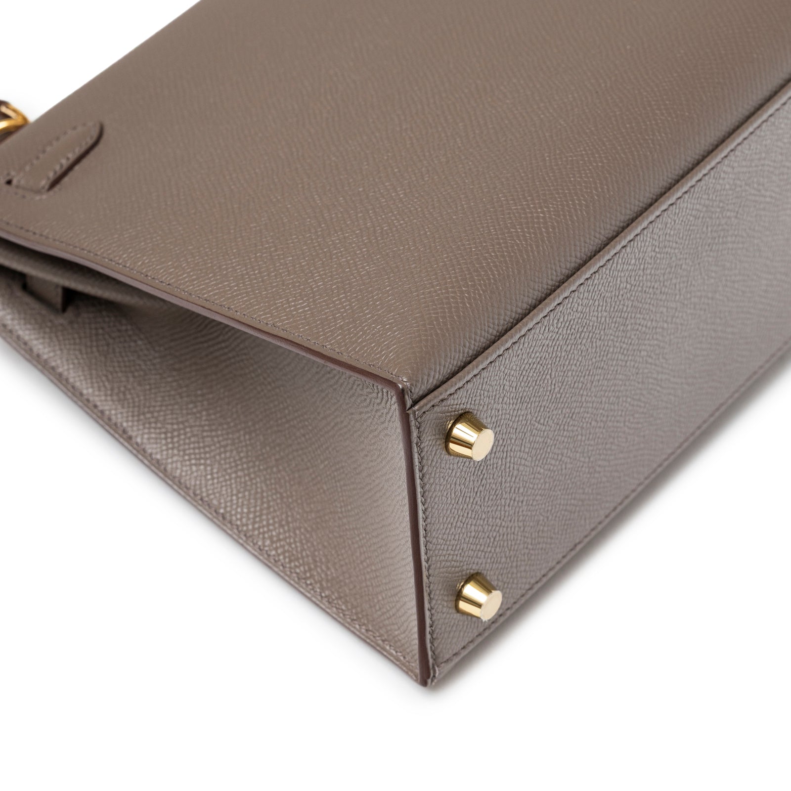 Close-up of base corner on Hermès Kelly 25 Sellier Etain Epsom Gold Hardware showing gold protective feet detail