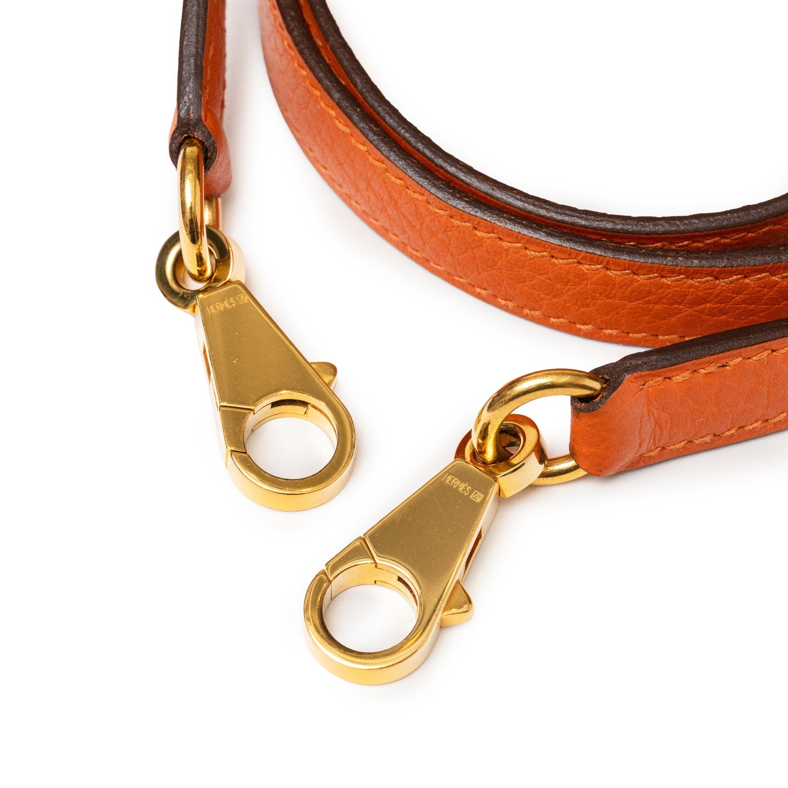 Close-up of gold hardware clasps and orange Clemence leather strap on Hermès Kelly 28 Retourne Orange Clemence Gold Hardware