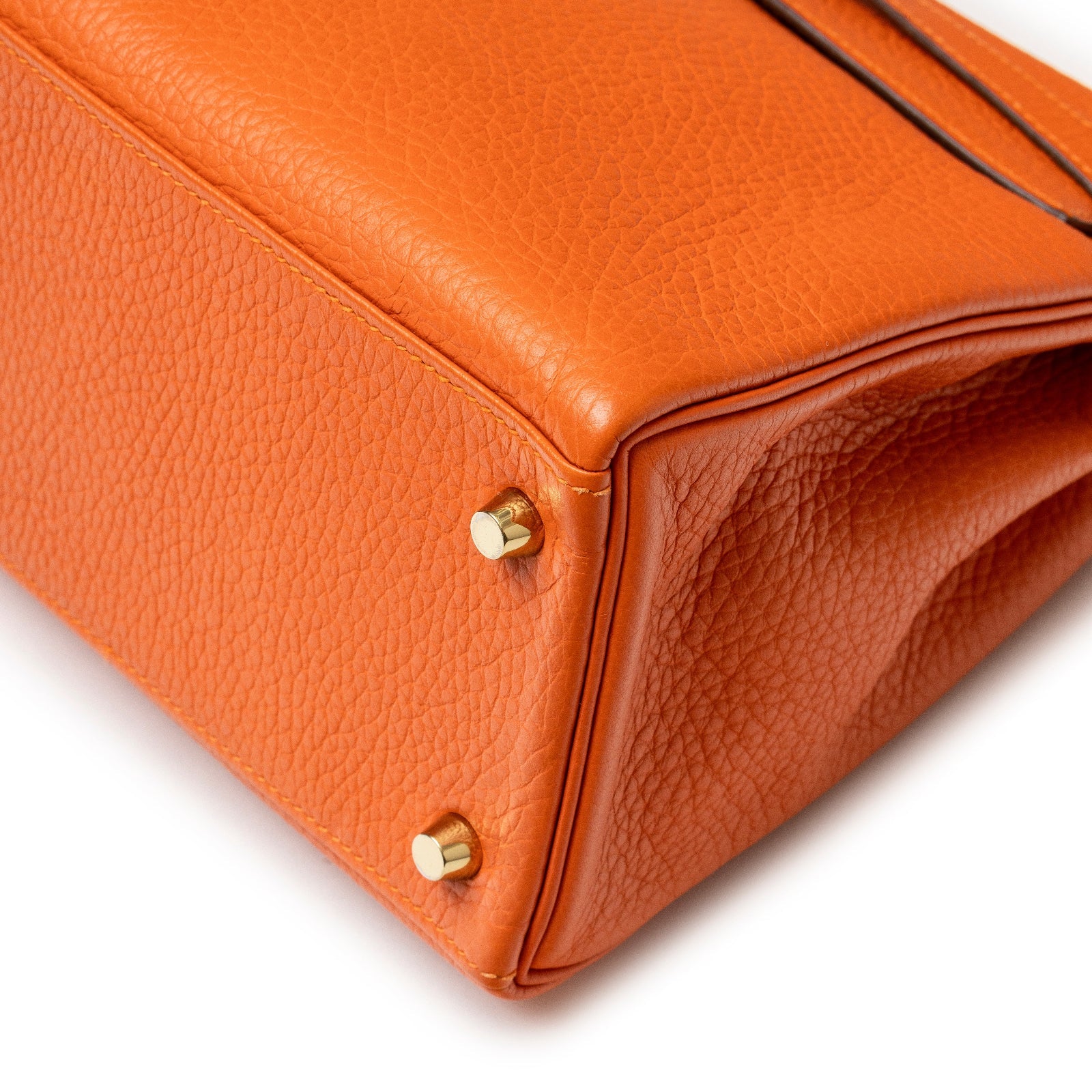 Close-up of bottom corner and gold hardware feet on Hermès Kelly 28 Retourne Orange Clemence Gold Hardware bag