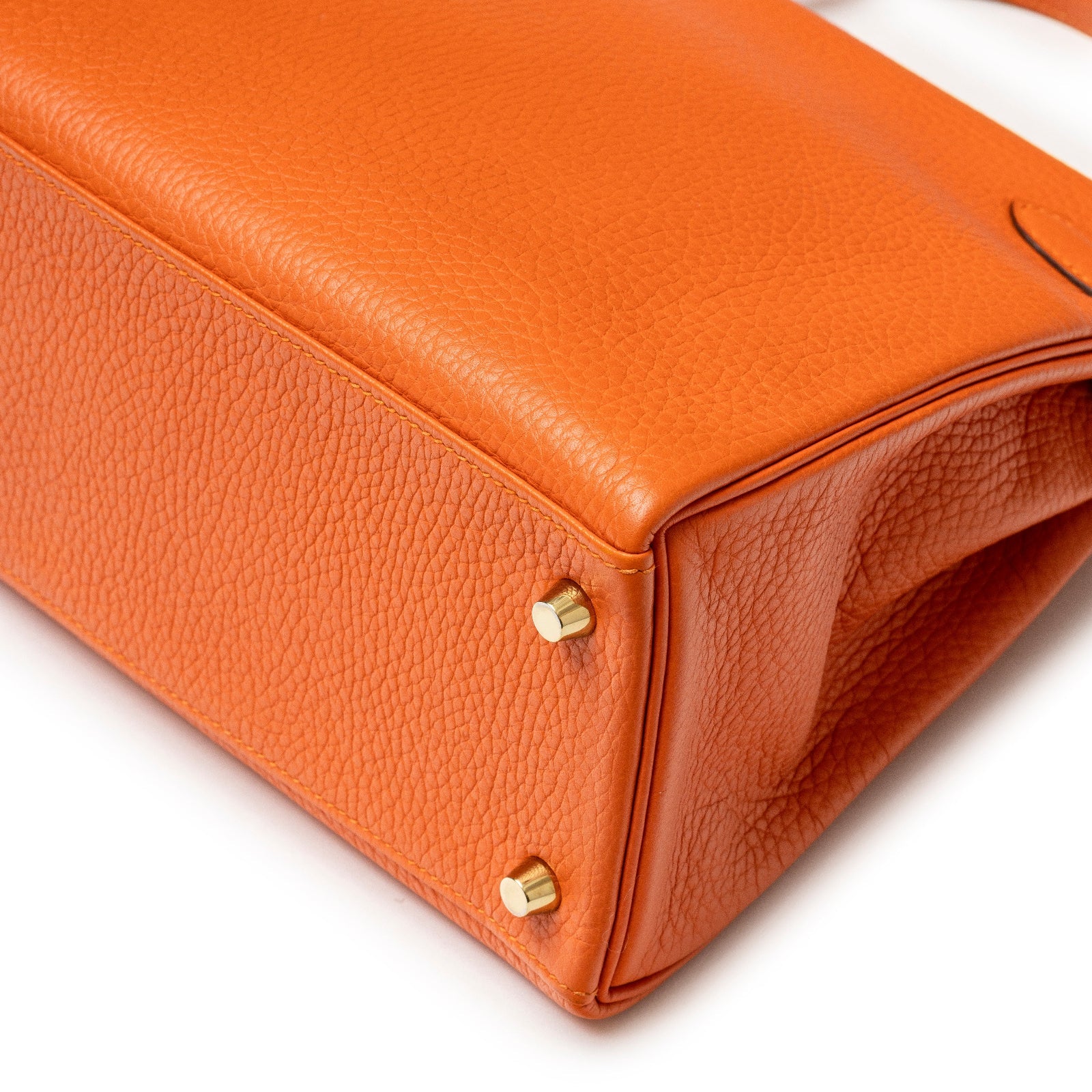 Close-up of bottom corner showing orange Clemence leather and gold hardware feet on Hermès Kelly 28 Retourne Orange Clemence Gold Hardware
