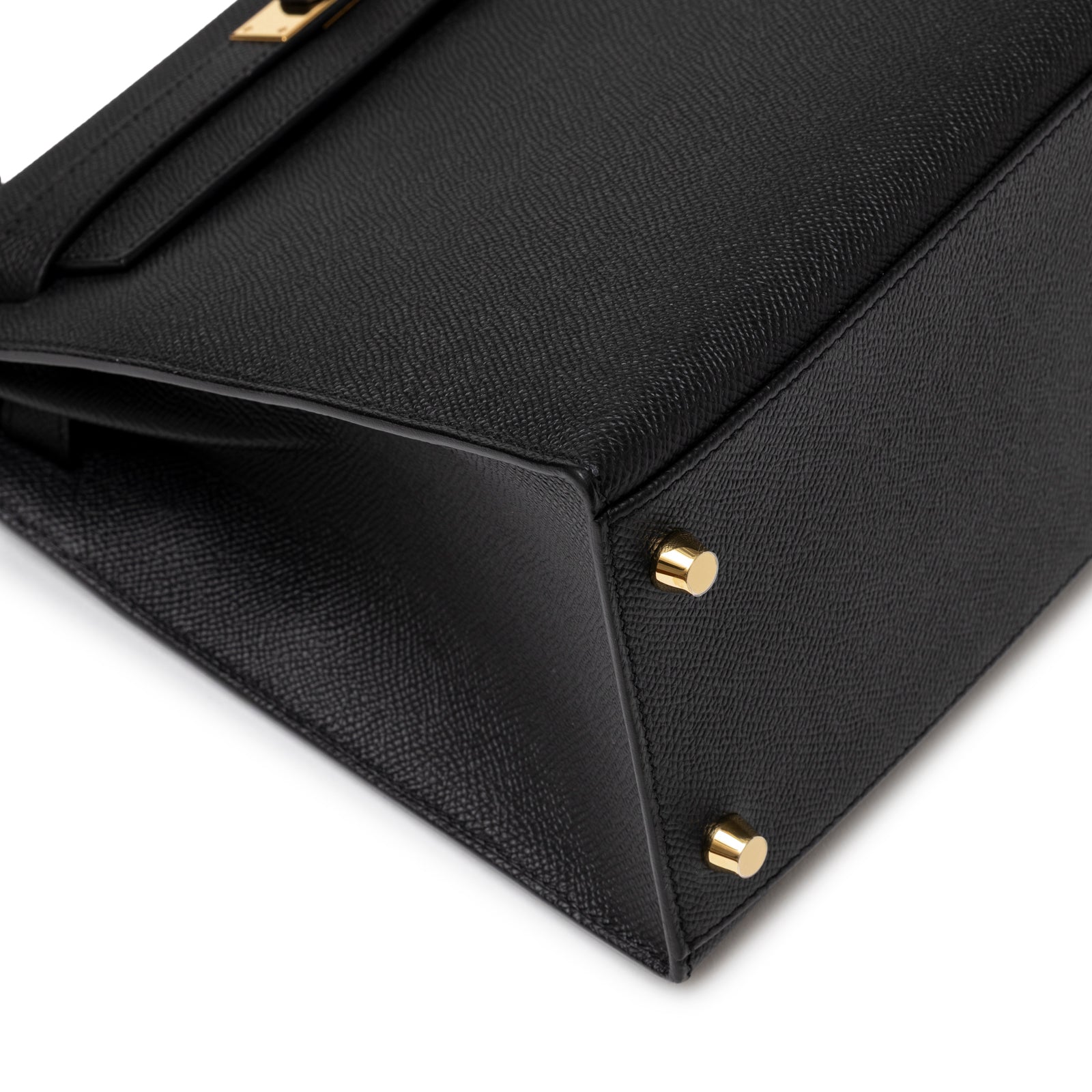 Close-up of bottom corner on Hermès Kelly 28 Sellier Black Epsom Gold Hardware showing gold feet and textured leather