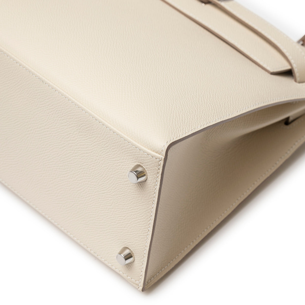 Close-up of bottom corner and feet on Hermès Kelly 28 Sellier Craie Epsom Palladium Hardware in cream leather