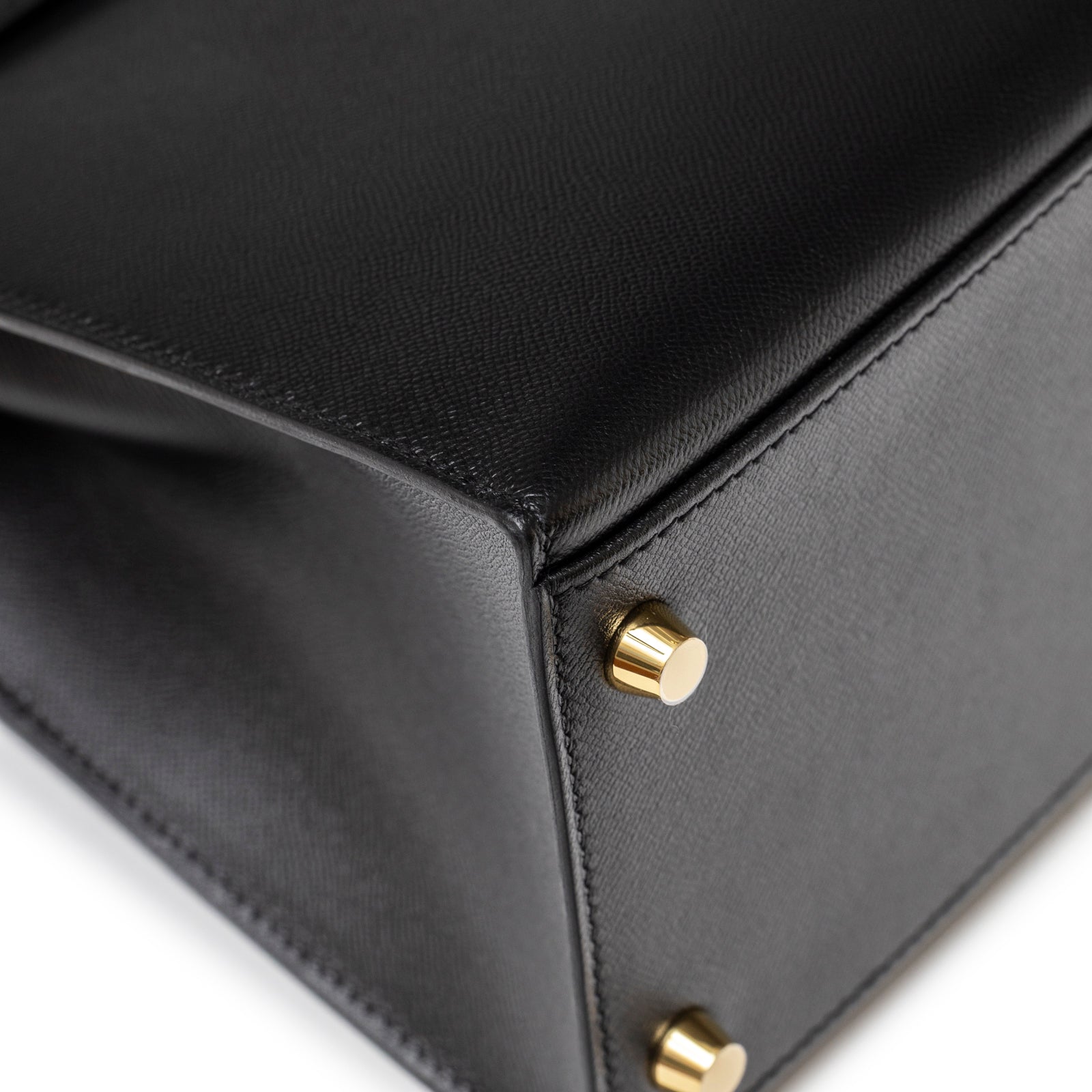Close-up of Hermès Kelly 28 Sellier Touch Black Madame Shiny Niloticus Crocodile Gold Hardware base corner with gold stud feet detail