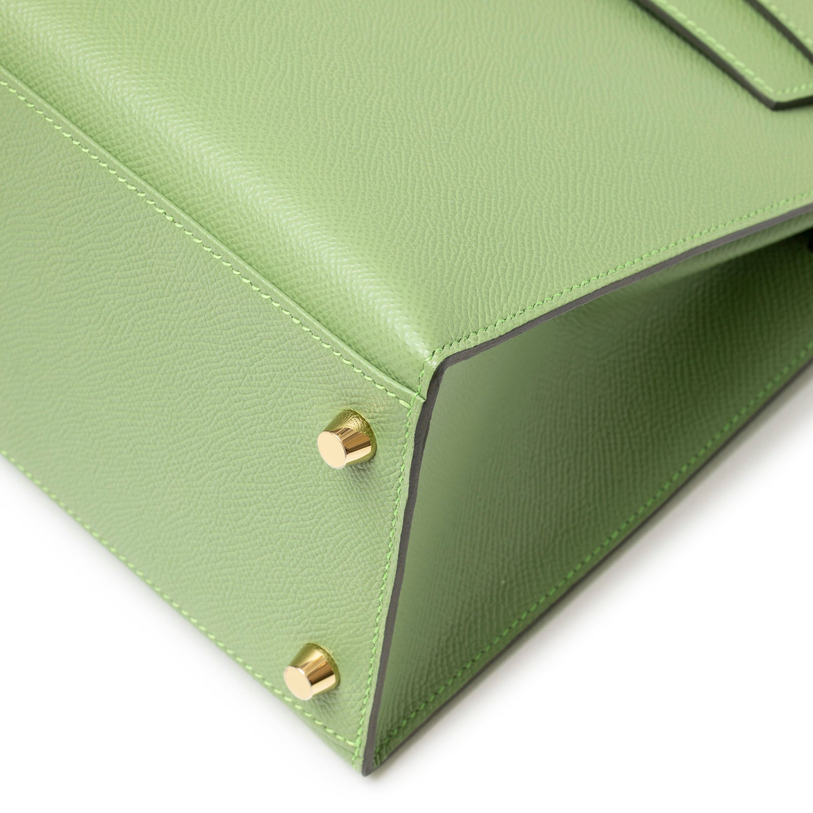 Close-up of bottom corner studs and textured green leather on Hermès Kelly 28 Sellier Vert Criquet Epsom Gold Hardware handbag