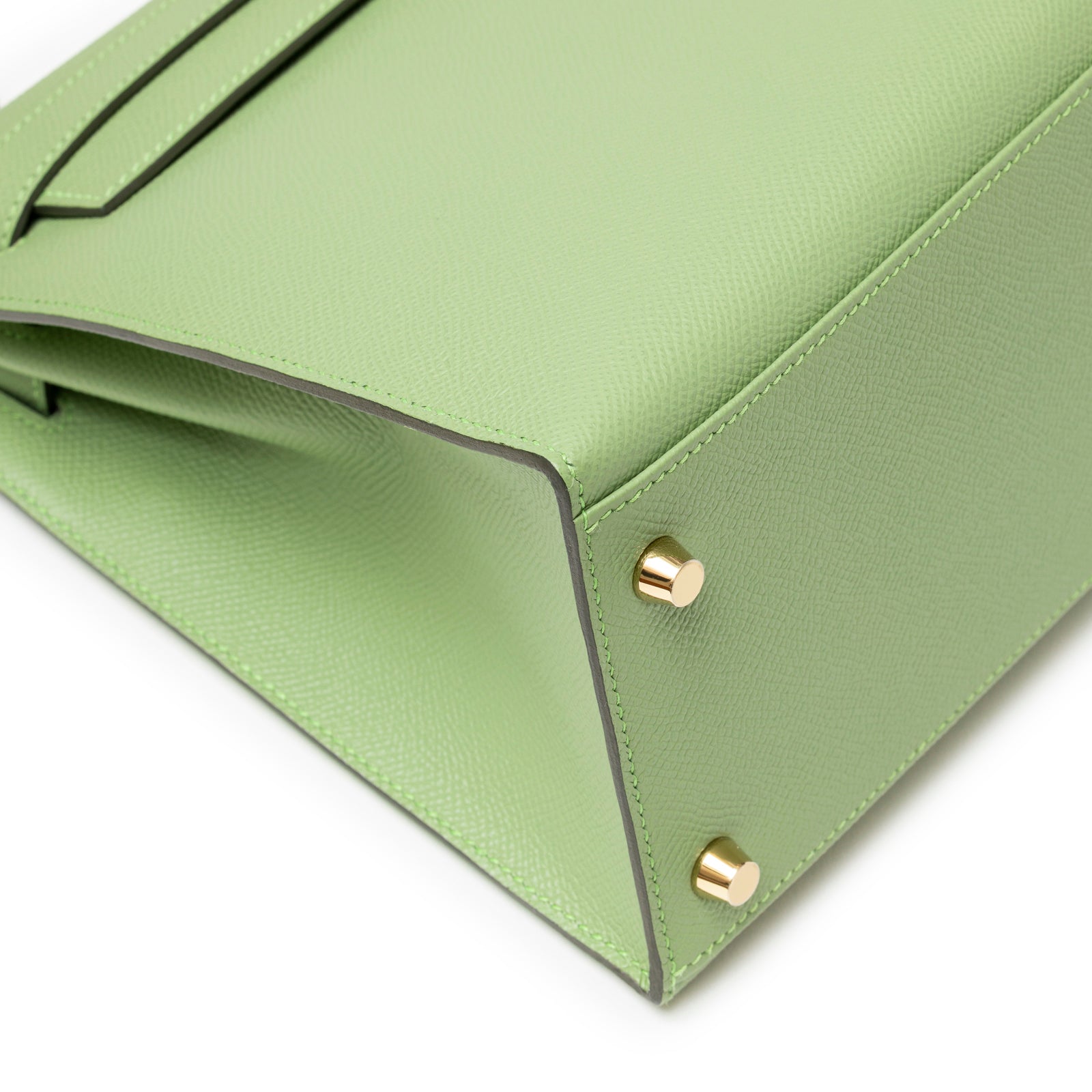 Close-up of bottom corner with gold hardware and textured green leather on Hermès Kelly 28 Sellier Vert Criquet Epsom Gold Hardware.
