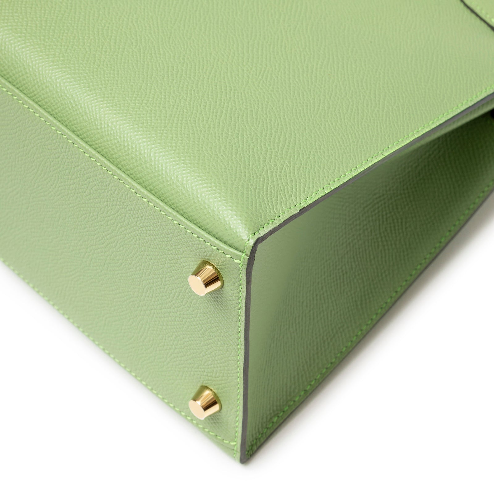 Close-up of base corner on Hermès Kelly 28 Sellier Vert Criquet Epsom Gold Hardware showing leather texture and gold feet detail