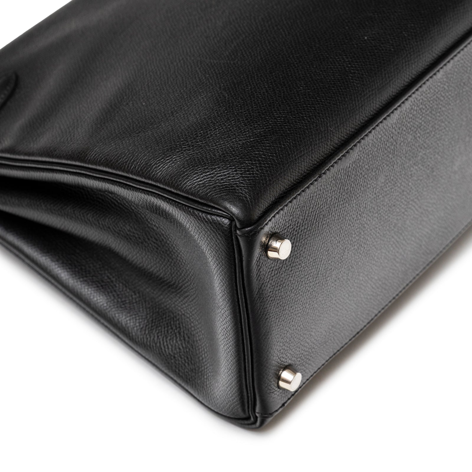 Close-up of black textured leather base corner and palladium metal studs on Hermès Kelly 32 Black Epsom Palladium Hardware