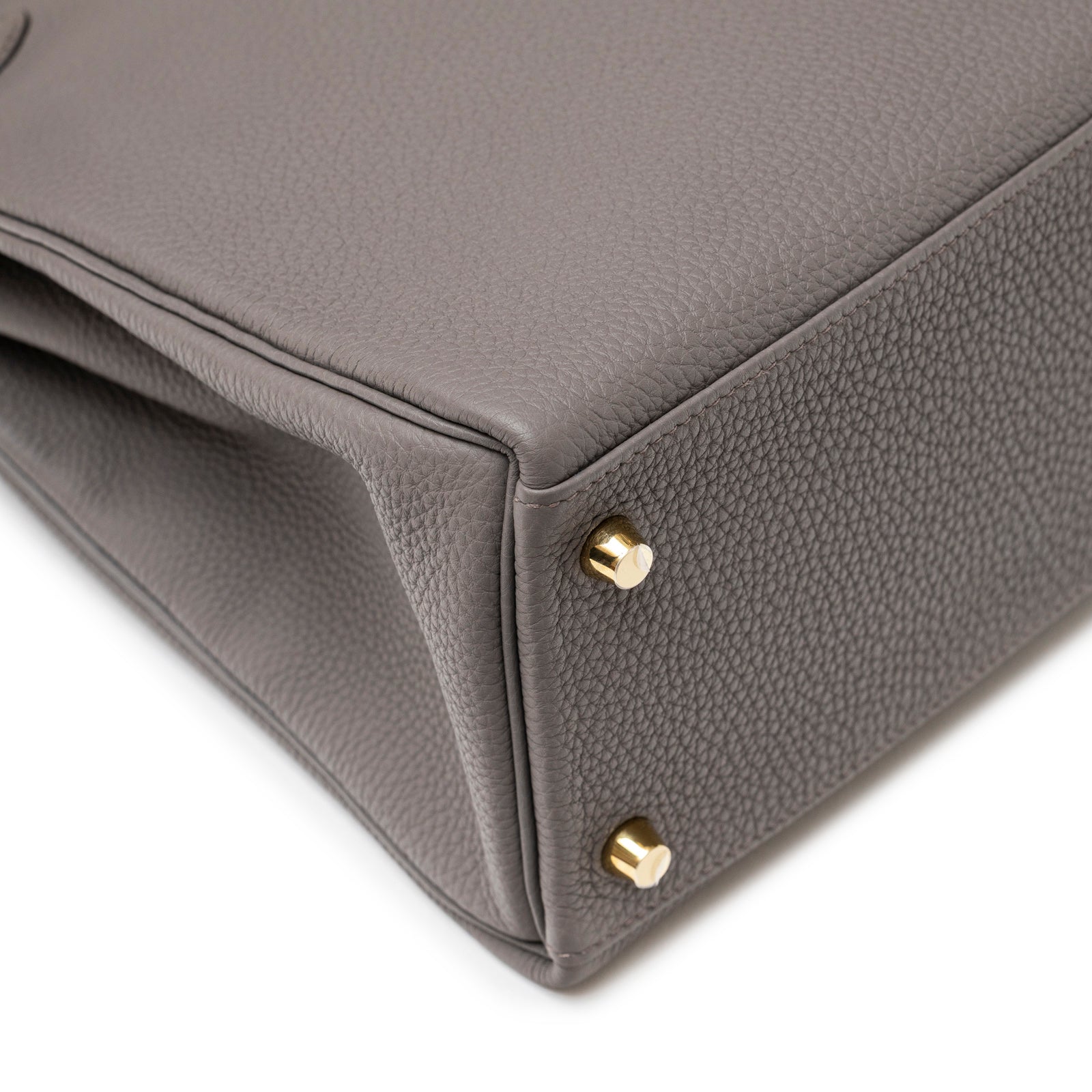 Close-up of bottom corner showing textured Etain Togo leather and gold hardware feet on Hermès Kelly 32 Retourne Etain Togo Gold Hardware.