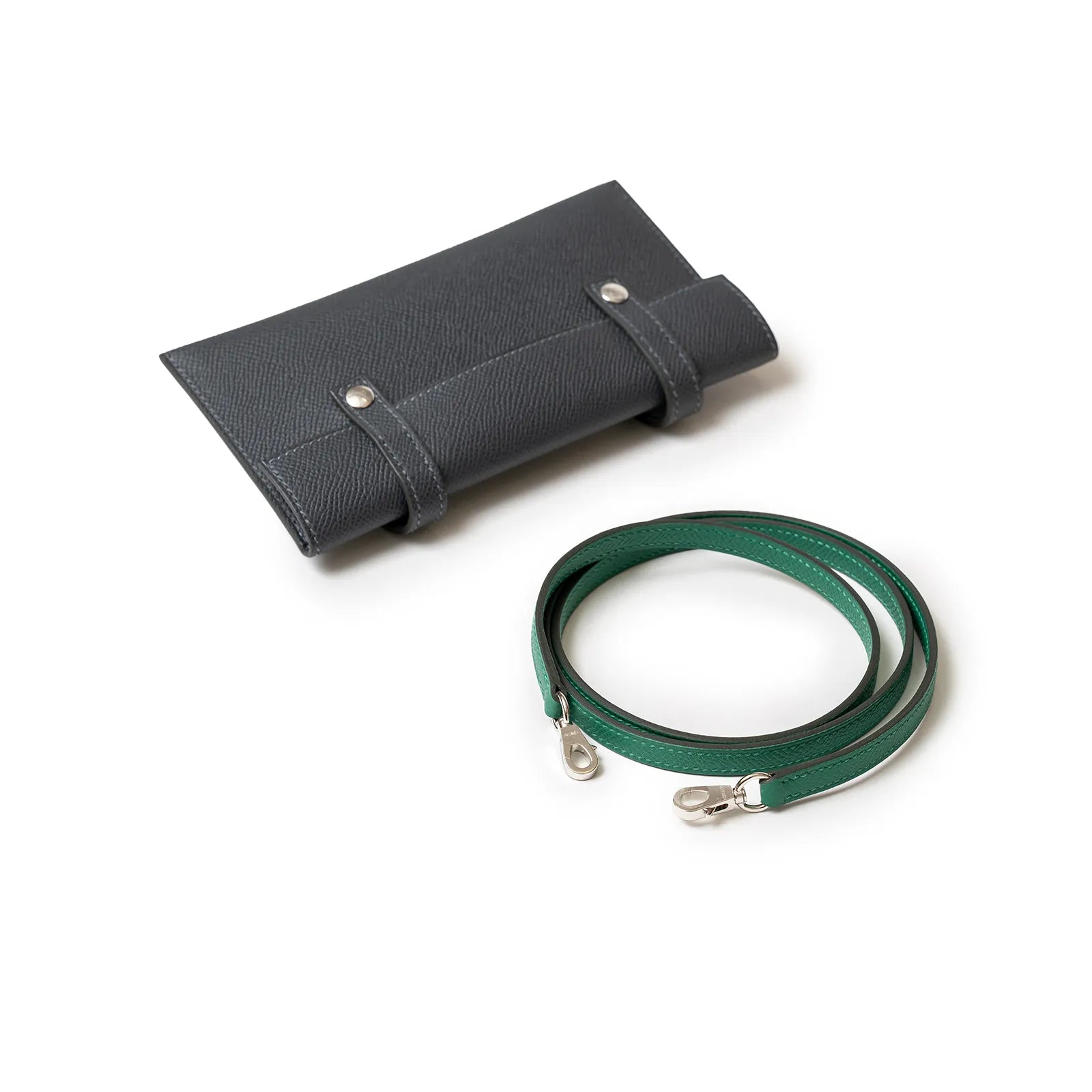 Dark gray leather pouch and green strap with silver clasps on white background.