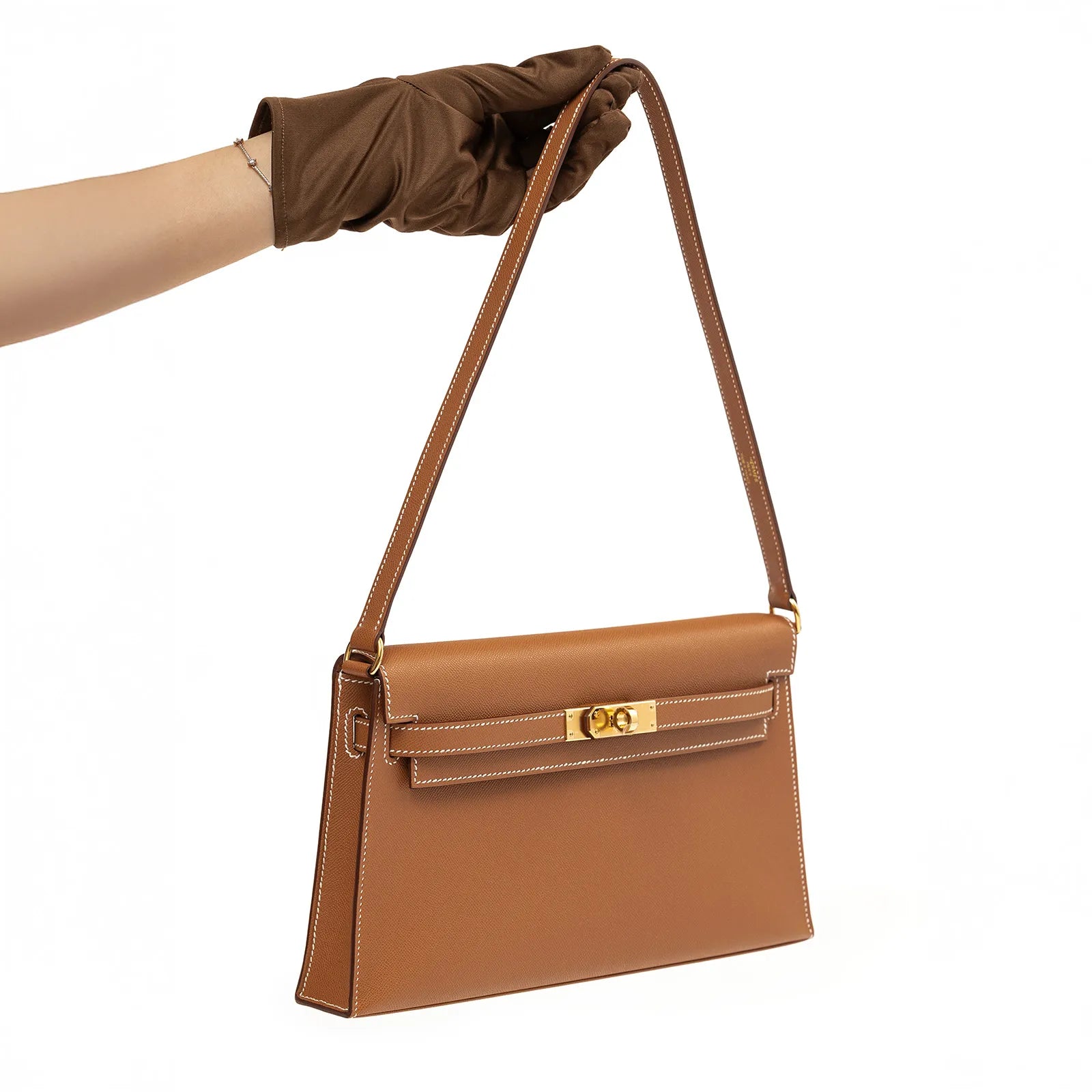 Angled shot of Hermès Kelly Elan Gold Madame Gold Hardware in smooth tan leather with gold clasp held by gloved hand