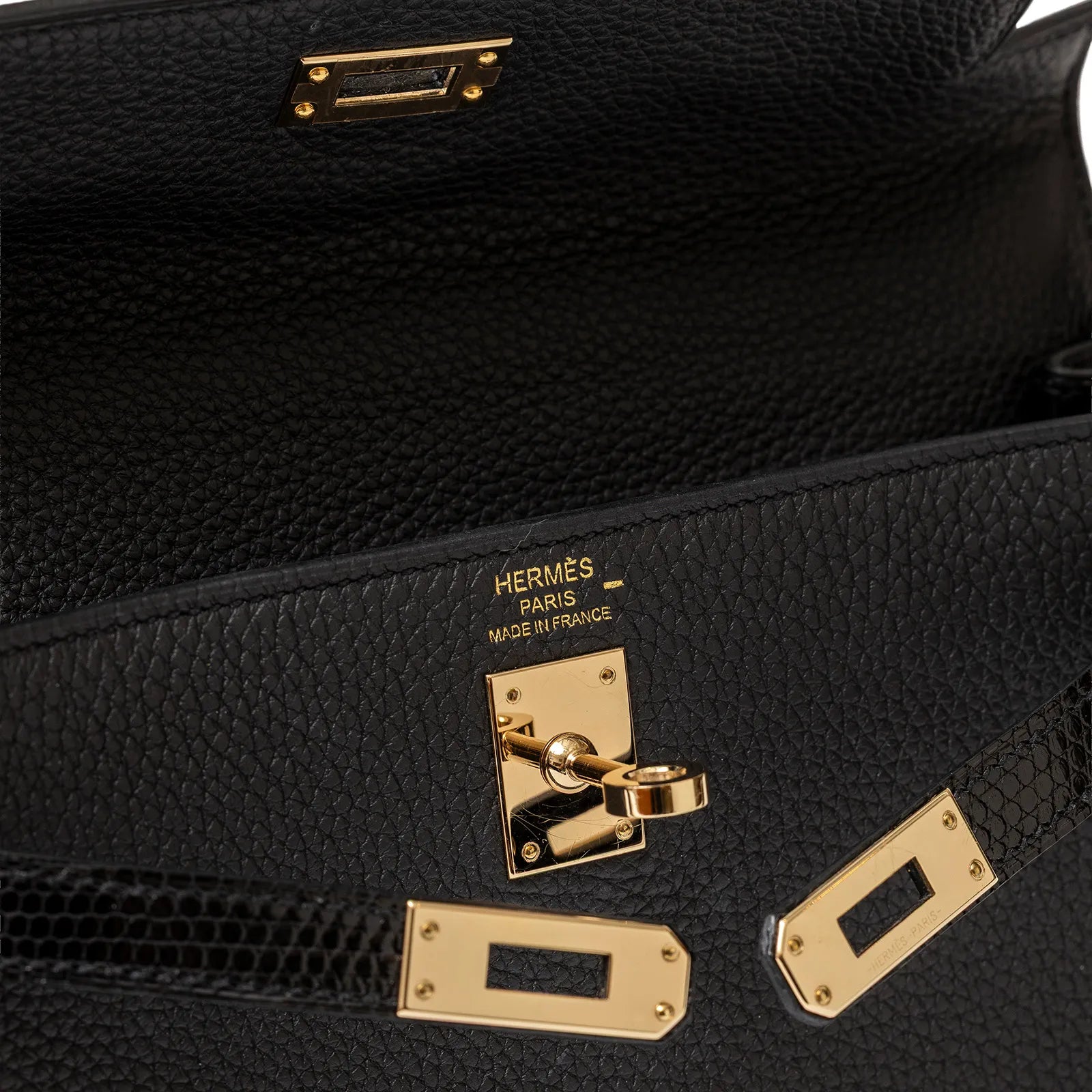 Close-up of Hermès Kelly 25 Retourne Black Touch Togo/Lizard Permabrass Hardware interior with gold hardware details and Hermès logo.