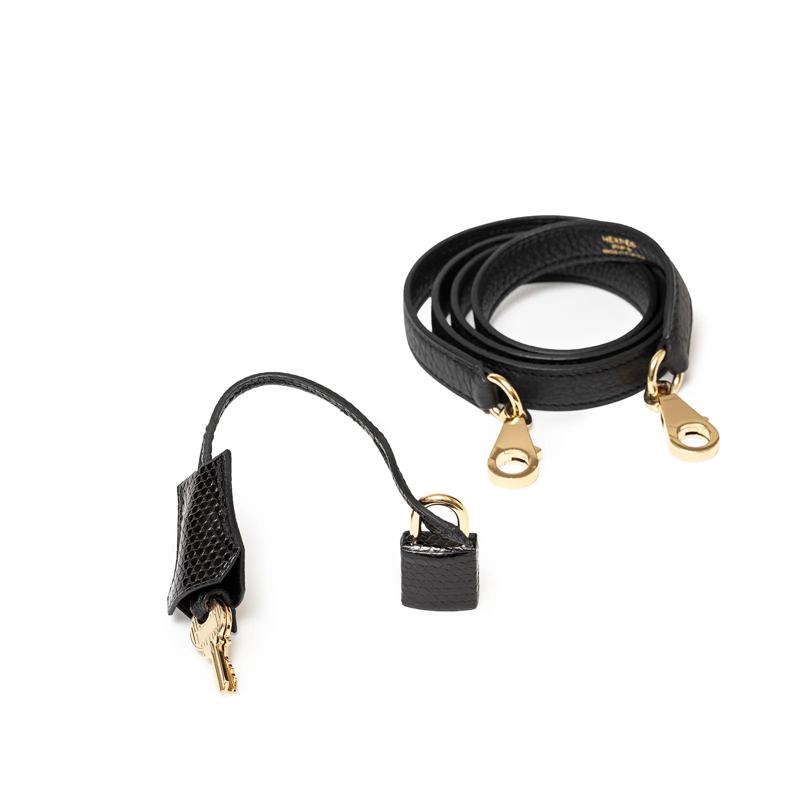 Black leather strap with gold clasps beside a matching key holder on a white background.