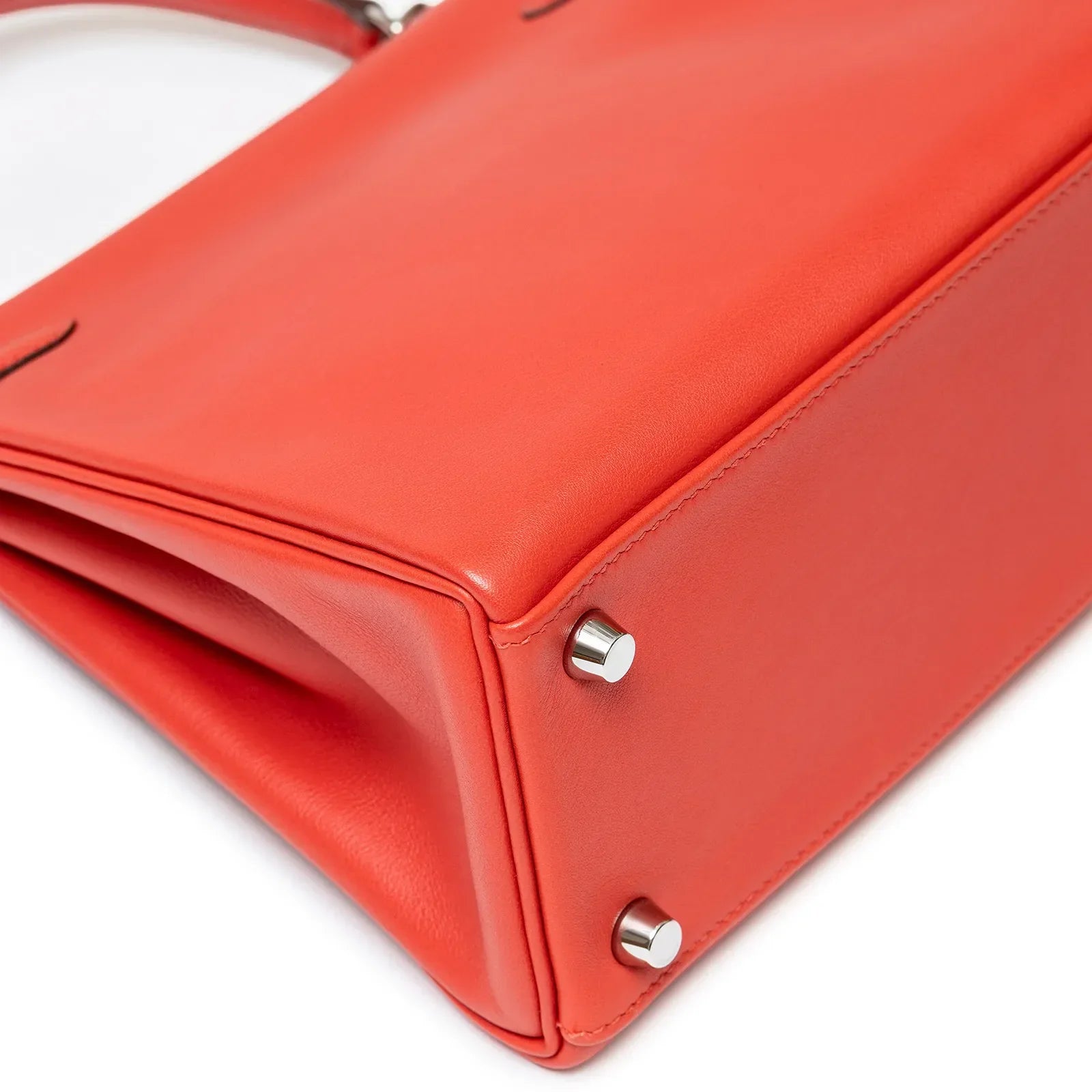 Close-up angled shot of the bottom corner showing stitching and palladium feet on Hermès Kelly 25 Retourne Rouge Swift Palladium Hardware