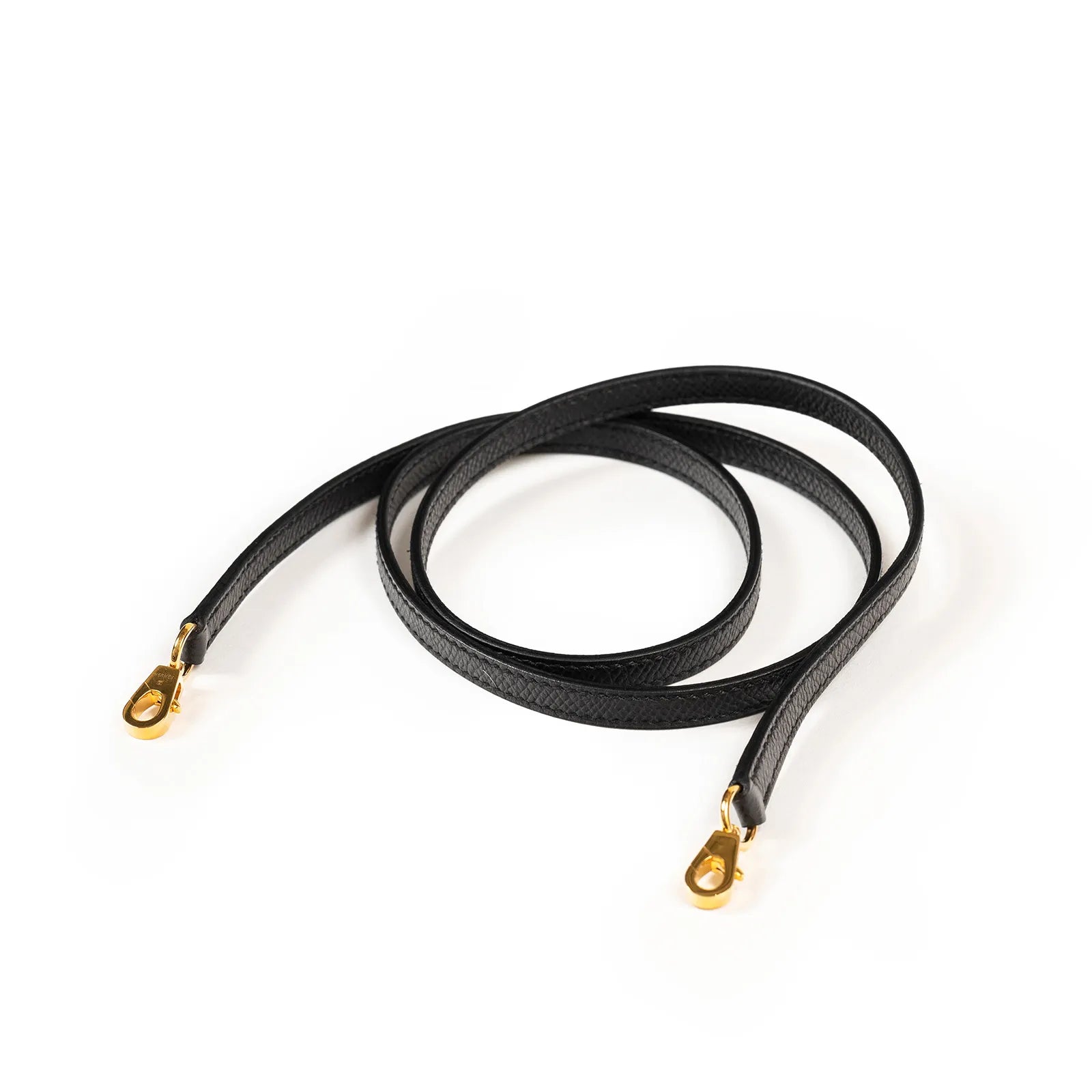 Black leather strap with gold clasps, coiled on a white background.