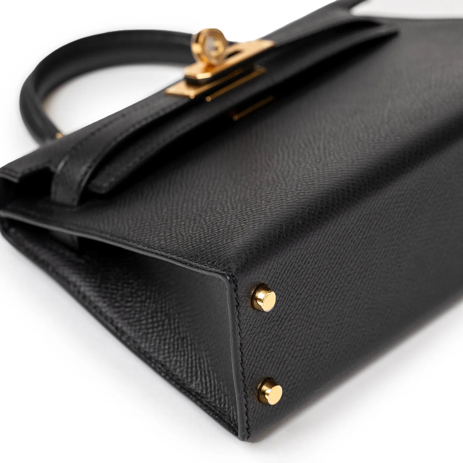 Black leather handbag, angled view with golden hardware details.