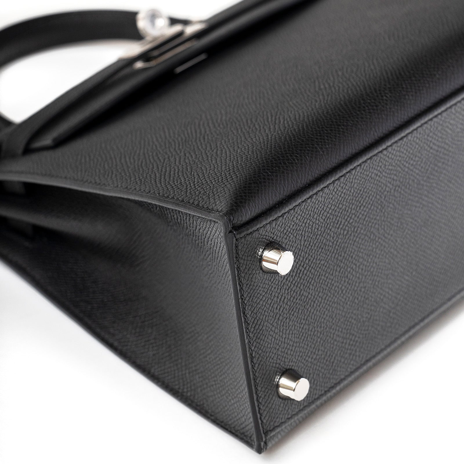 Close-up of bottom corner showing feet and black textured leather on Hermès Kelly 25 Sellier Black Epsom Palladium Hardware