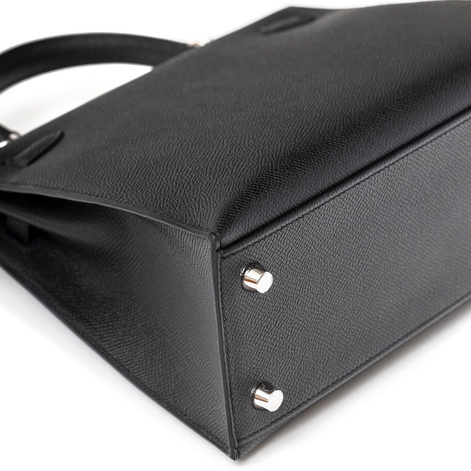 Close-up angled view of Hermès Kelly 25 Sellier Black Epsom Palladium Hardware showing bottom studs and texture