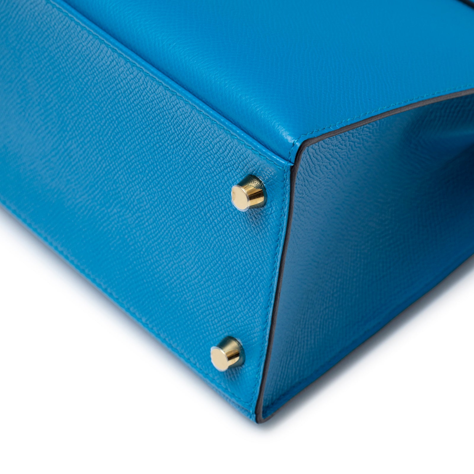 Close-up of bottom corner on Hermès Kelly Sellier 28 Blue Zanzibar Epsom Gold Hardware showing textured leather and gold feet