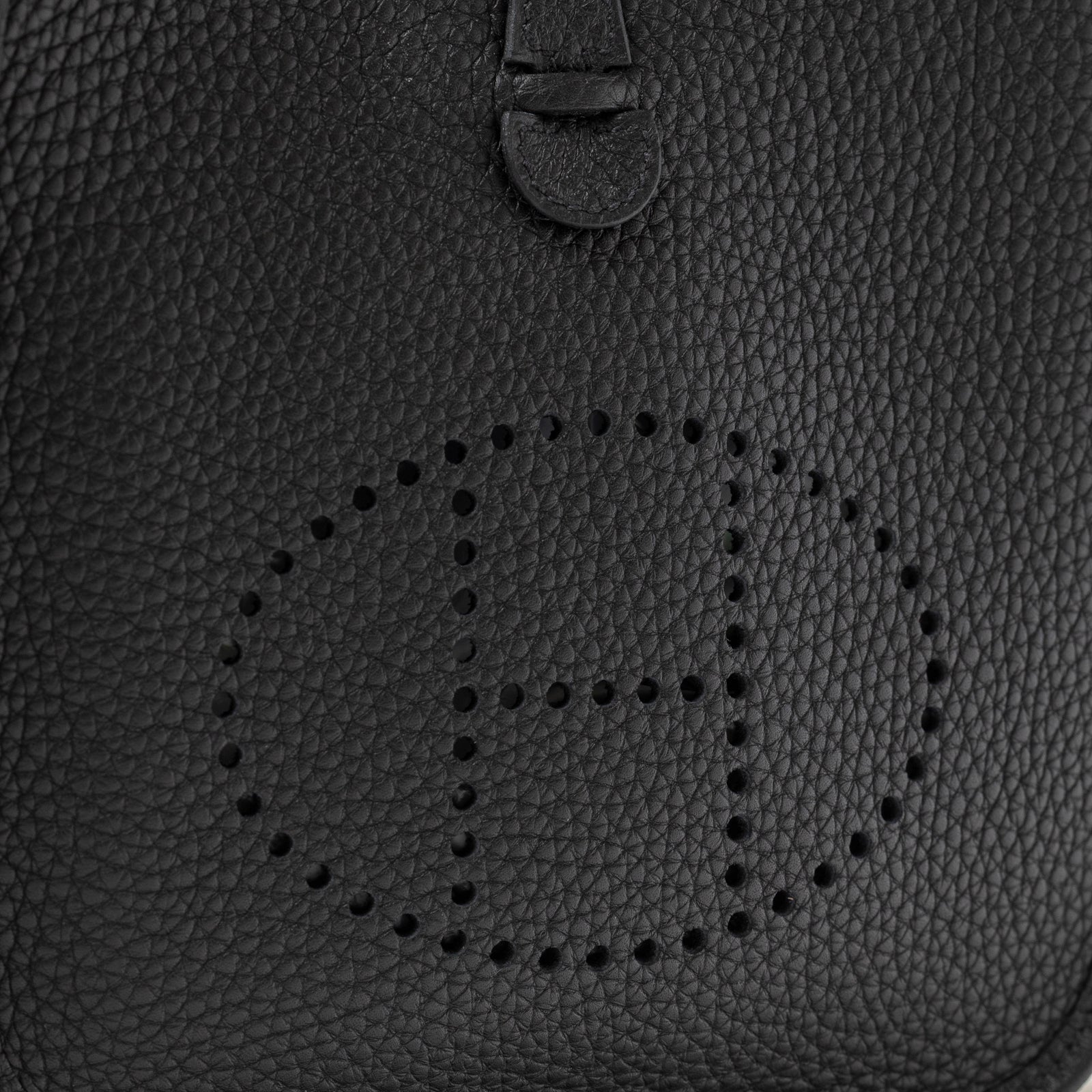 Close-up of Hermès Mini Evelyne Black Clemence Palladium Hardware showing perforated H logo and textured leather surface