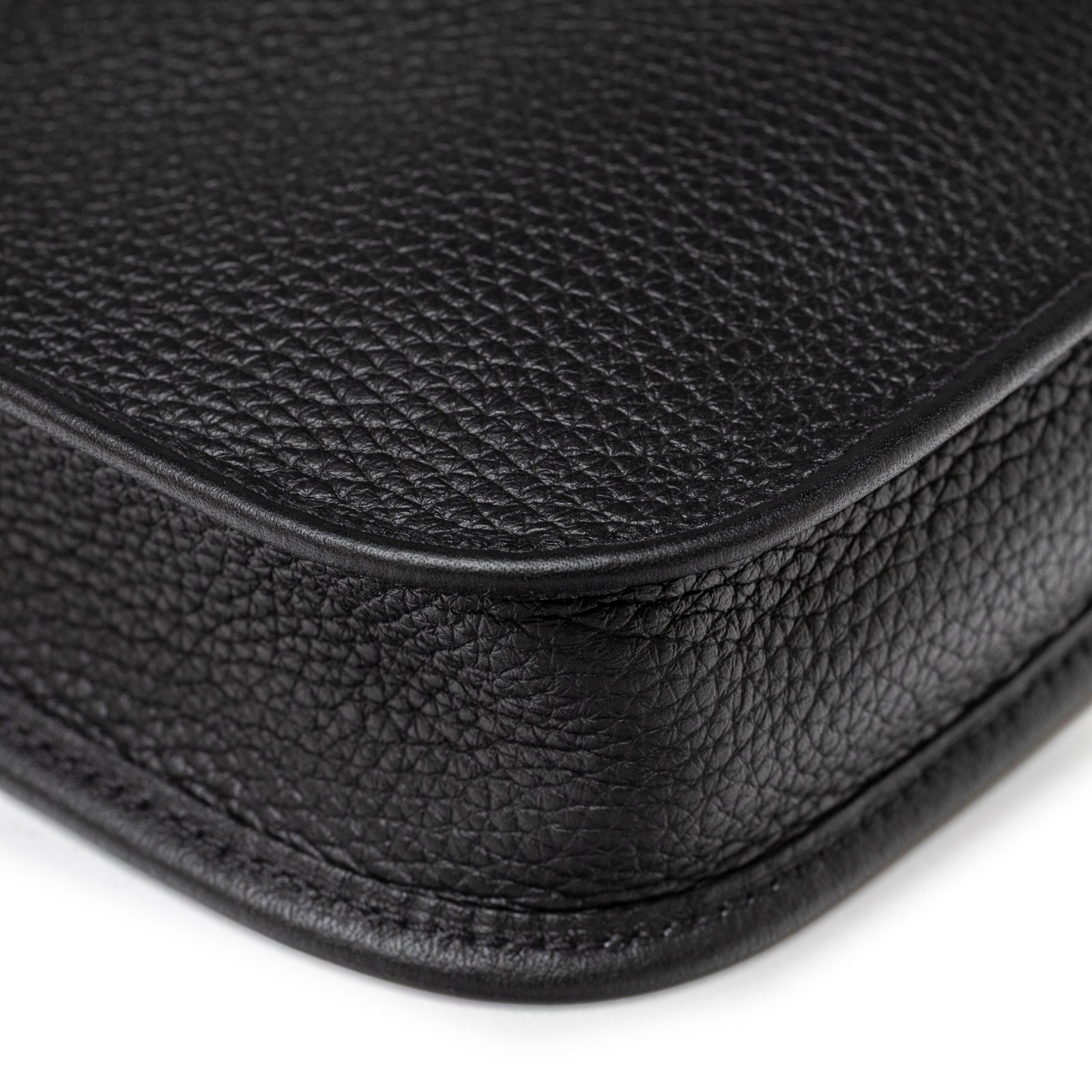 Textured grain close-up of Hermès Mini Evelyne Black Clemence Palladium Hardware rounded leather corner with precise stitching detail