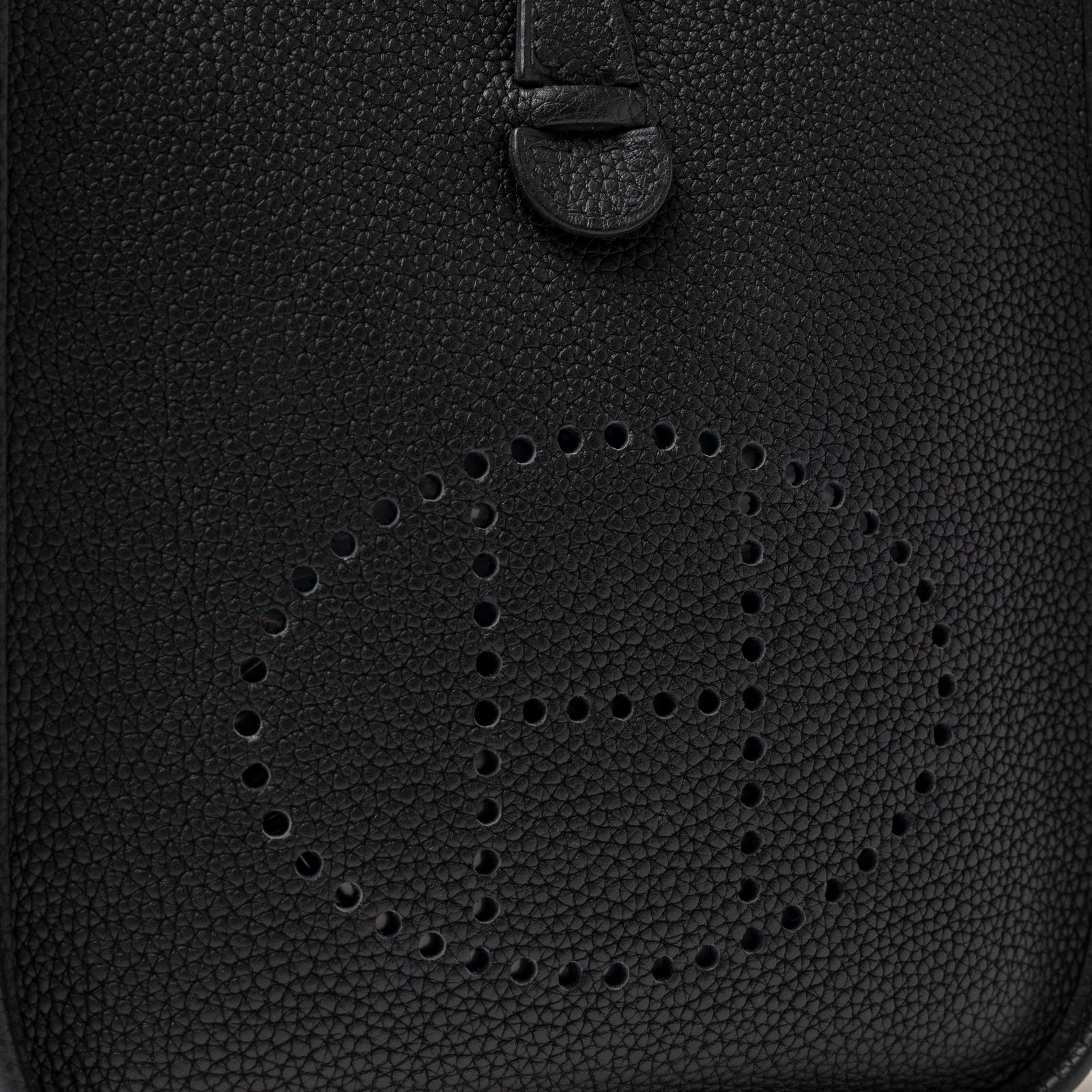 Close-up of perforated H logo detail and pebbled leather texture on Hermès Mini Evelyne Caban Blue Zellige Indigo Clemence Palladium Hardware