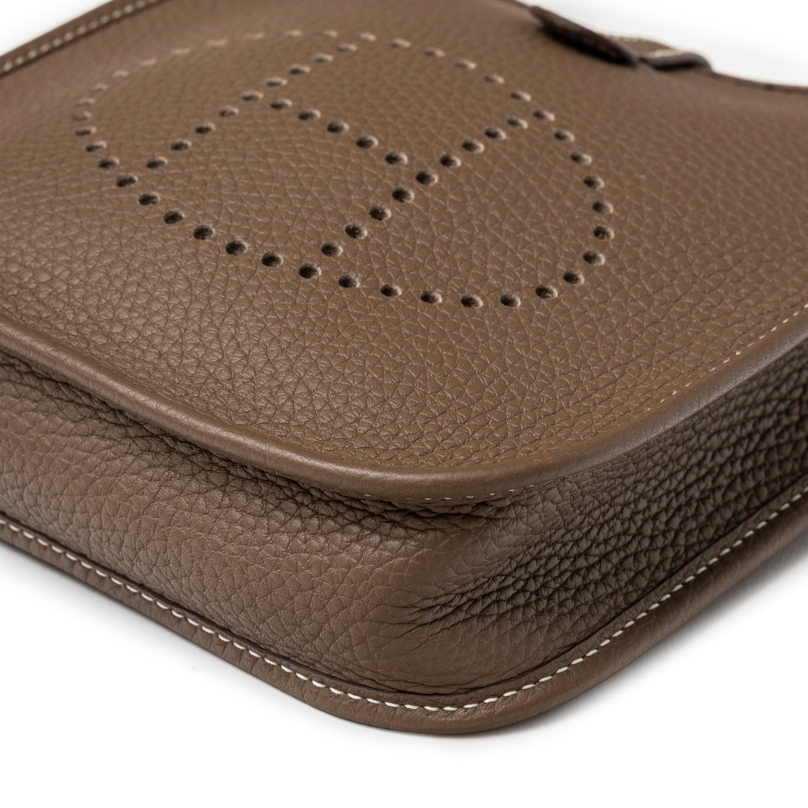 Close-up of Hermès Mini Evelyne Etoupe Blue Indigo Clemence Gold Hardware showing pebbled leather and perforated logo detail