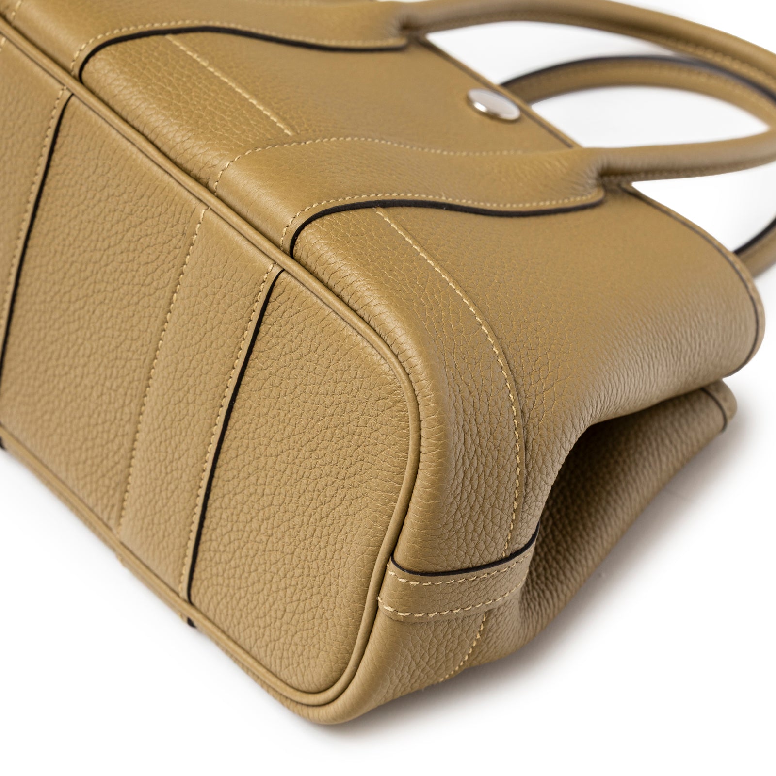 Close-up view of bottom corner and textured taupe leather with stitching on Hermès Mini Garden Party Neo 23 Dune Negonda Palladium Hardware