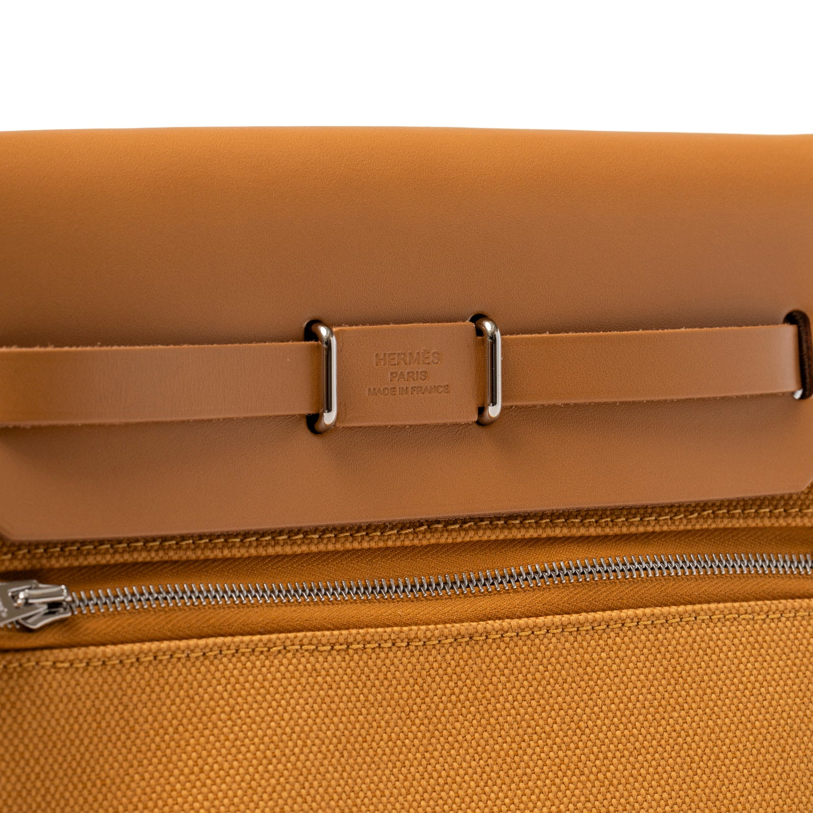 Close-up of leather strap and silver hardware engraved with Hermès Paris on Mini Herbag Zip 20 Naturel Sable Toile and Vache Hunter Palladium Hardware