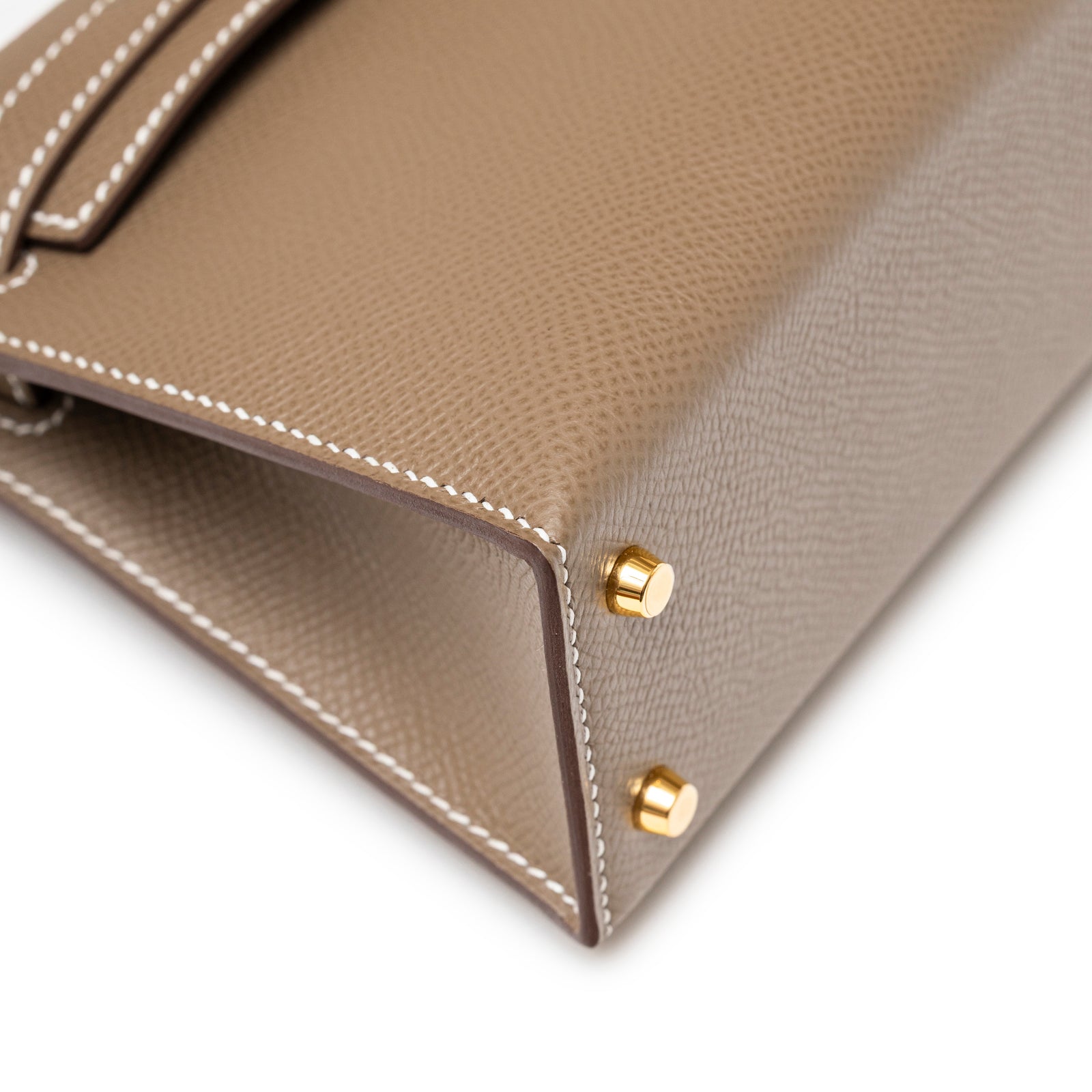 Close-up of Hermès Mini Kelly II Sellier Etoupe Epsom Gold Hardware bottom corner showing gold feet and white stitching detail