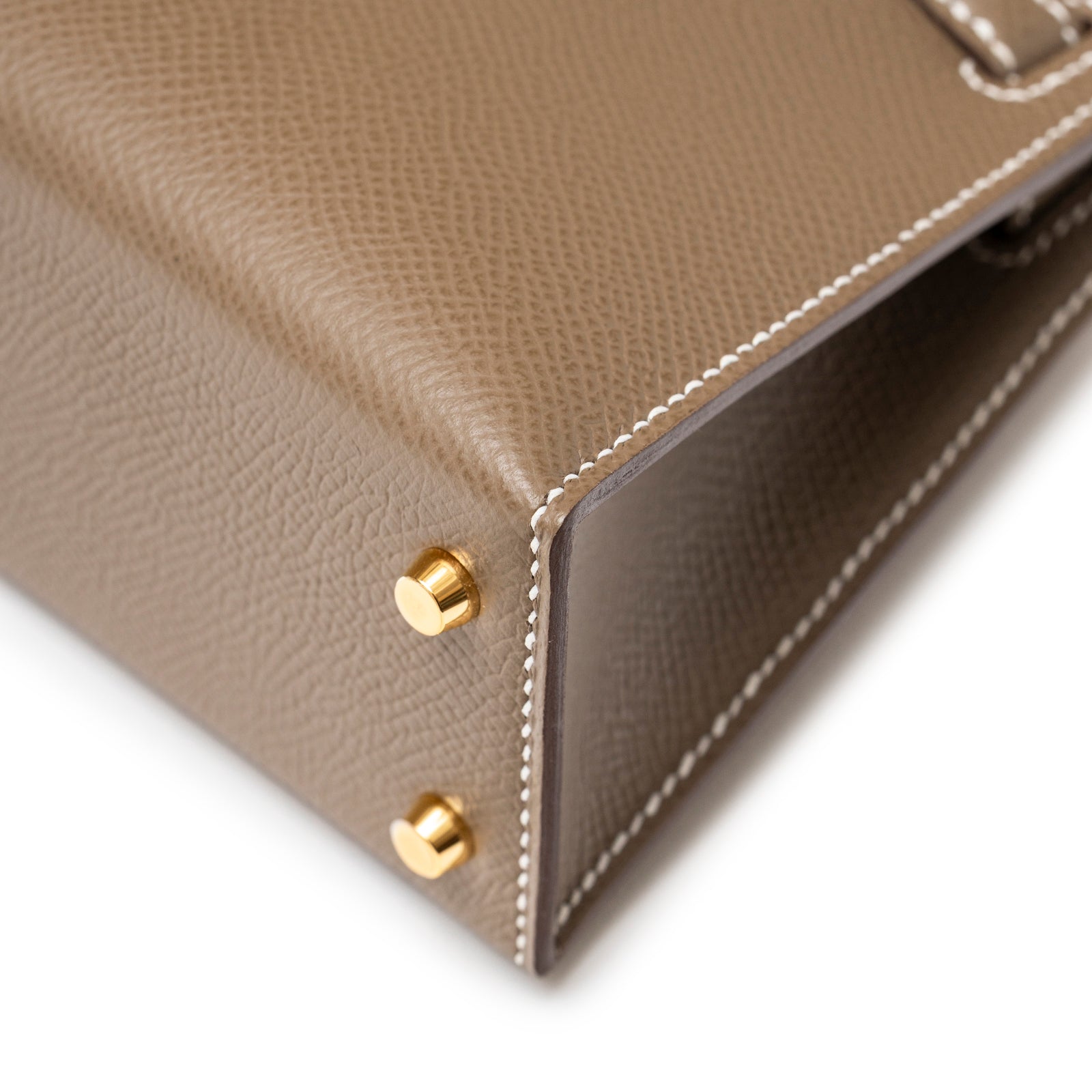 Close-up of Hermès Mini Kelly II Sellier Etoupe Epsom Gold Hardware showing corner with gold feet and white stitching detail