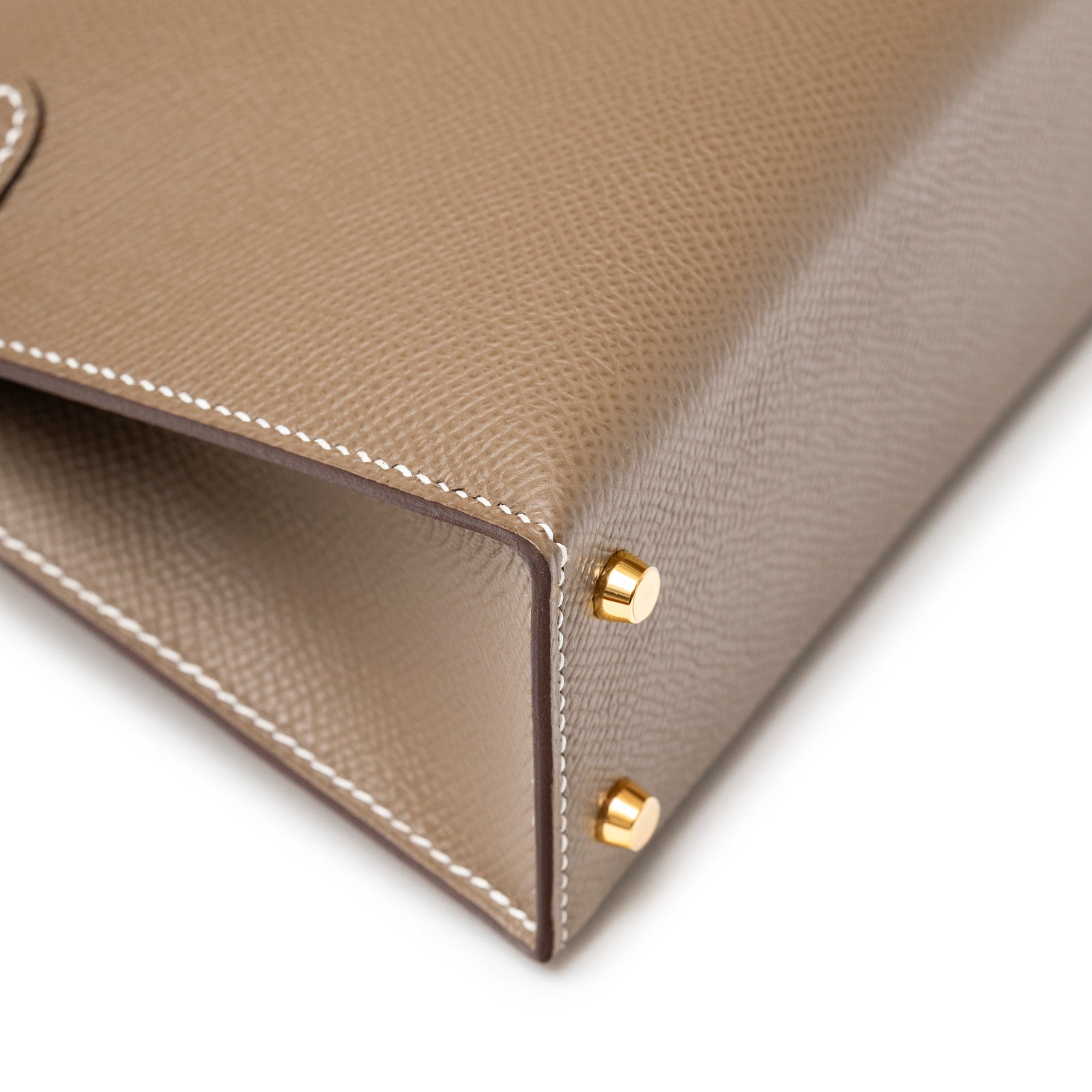 Close-up of Hermès Mini Kelly II Sellier Etoupe Epsom Gold Hardware corner showing gold feet and white stitching detail