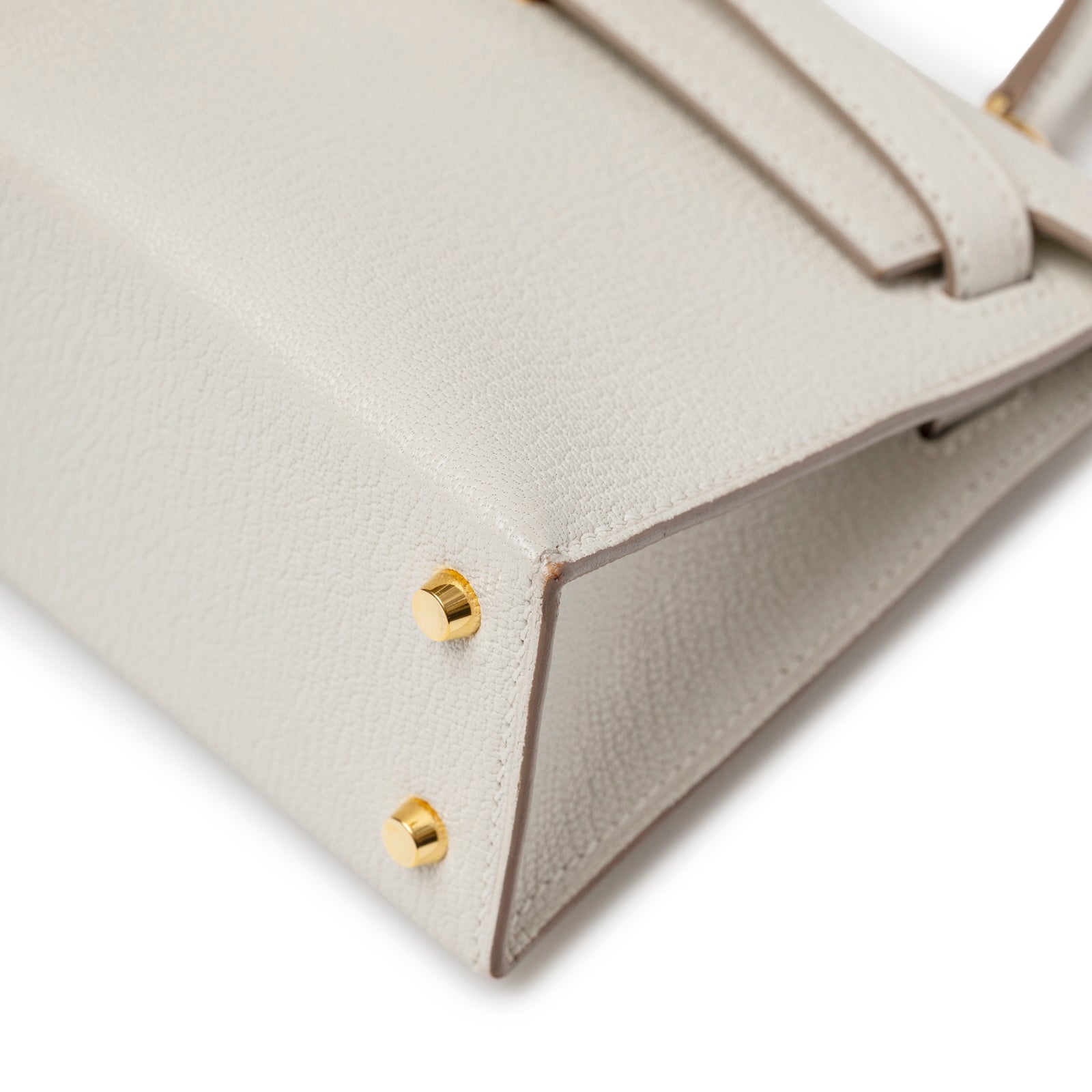 Close-up of base corner on Hermès Mini Kelly II Sellier Mushroom Chevre Mysore Gold Hardware showing gold feet and textured leather detail