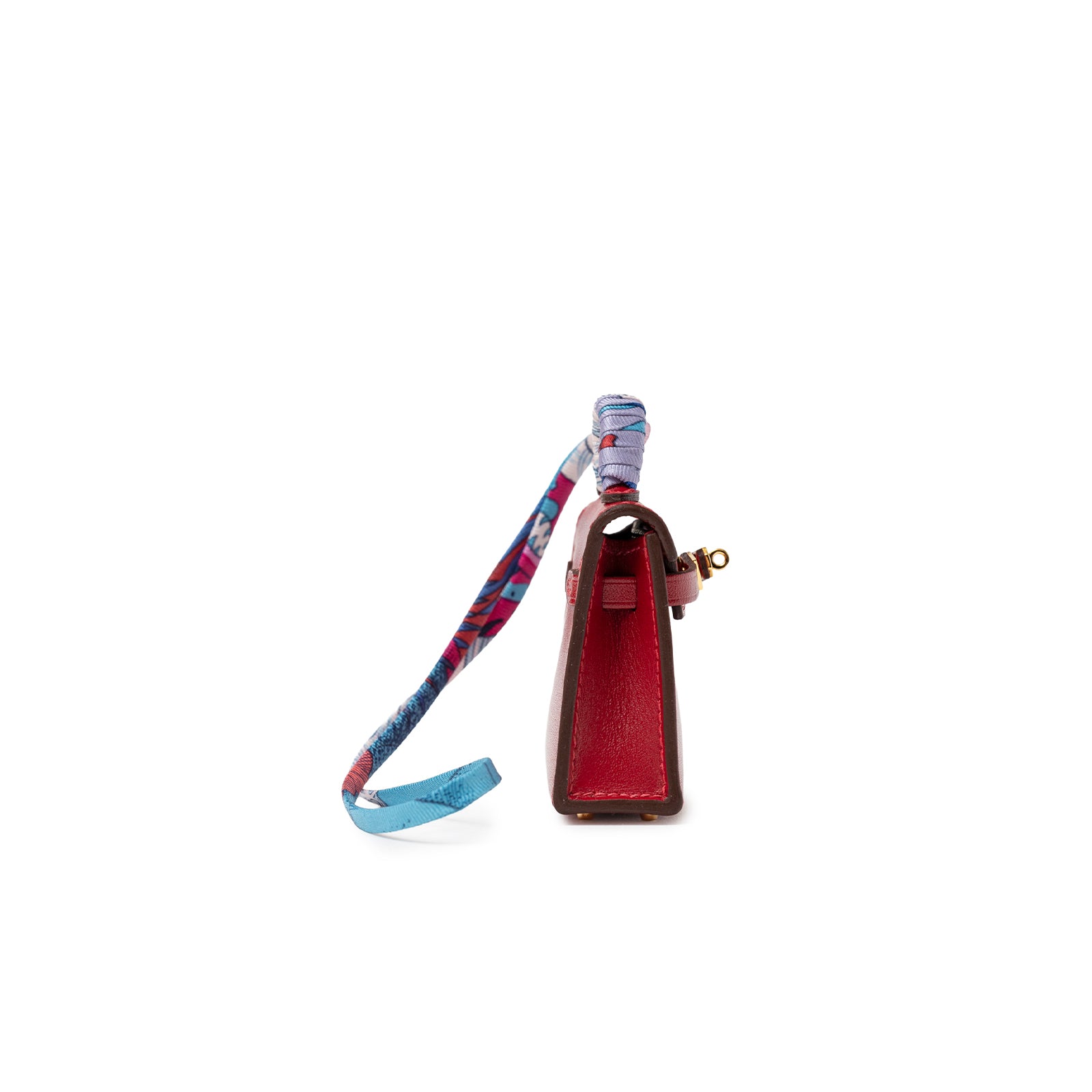 Side view of Hermès Mini Kelly Twilly Bag Charm Rouge Tadelakt Gold Hardware with colorful silk strap looped