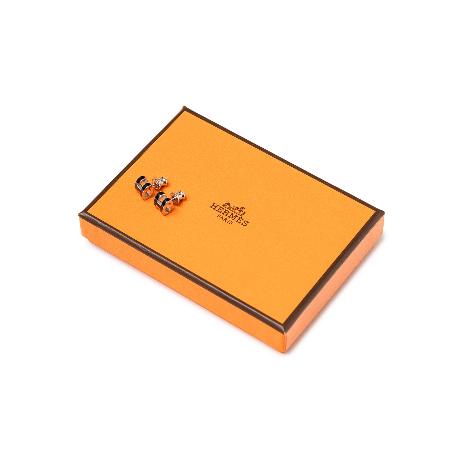 Hermès Mini Pop H Earrings Black Palladium Plated resting on an orange Hermès box.