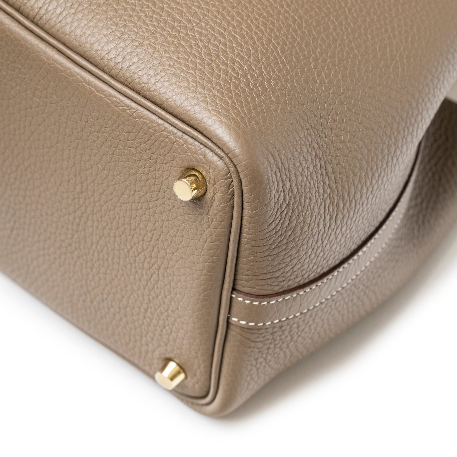 Close-up of the Hermès Picotin 18 Etoupe Clemence Gold Hardware corner showing textured leather and gold feet details.