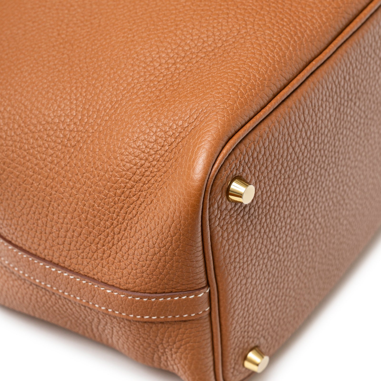 Close-up of corner detailing showing textured leather grain and polished gold feet on Hermès Picotin 18 Gold Clemence Gold Hardware