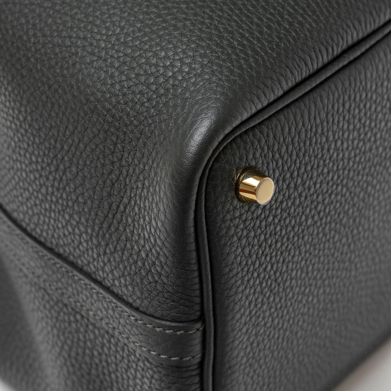 Close-up of textured leather and gold hardware feet on Hermès Picotin 18 Vert Fonce Clemence Gold Hardware handbag corner.