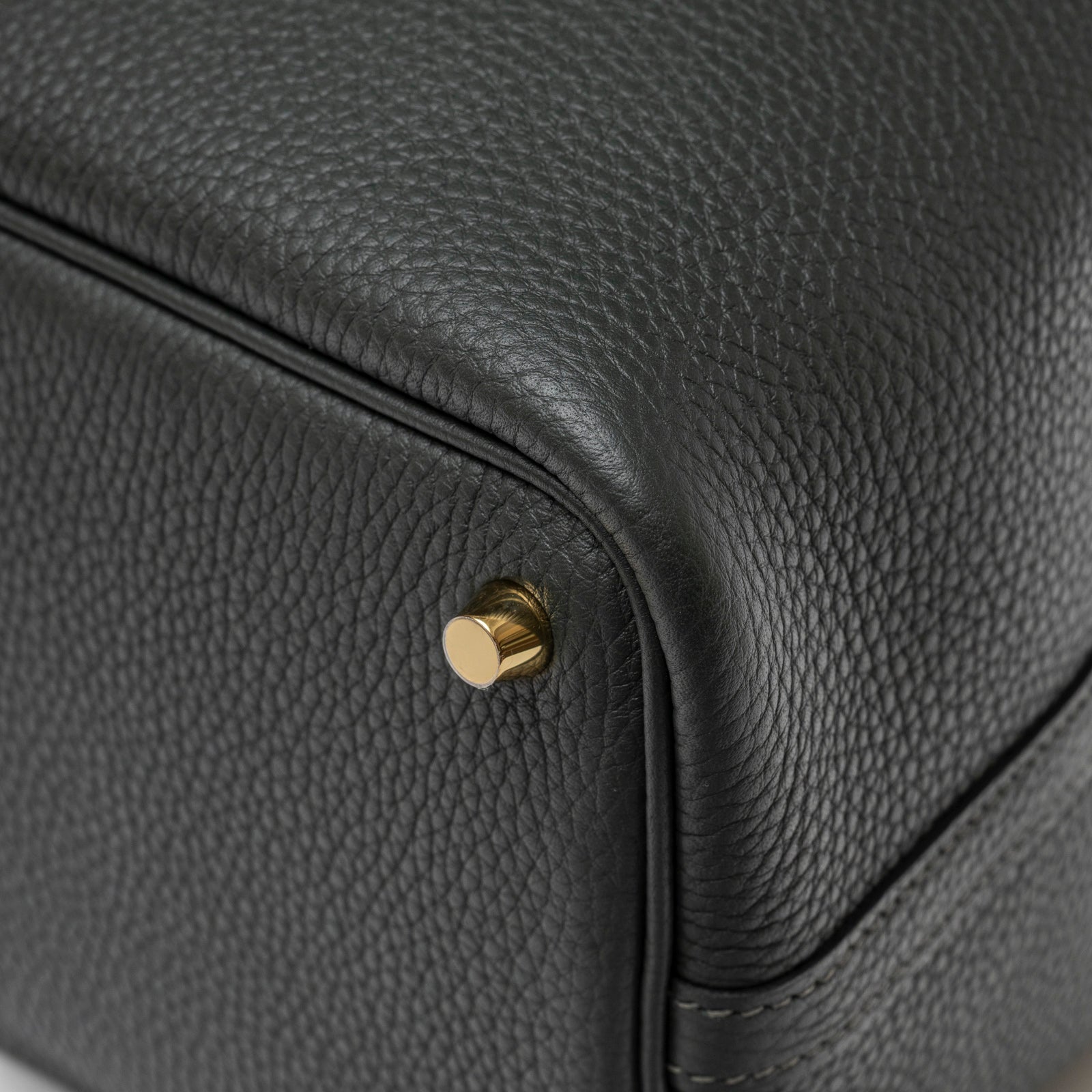 Close-up of Hermès Picotin 18 Vert Fonce Clemence Gold Hardware leather base corner with gold metal stud detail.