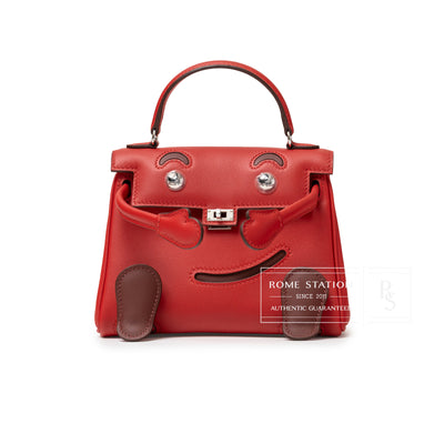 Front view of Hermès Quelle Idolle Kelly Doll Rouge Radieux Rouge H Swift Palladium Hardware bag with playful face design.