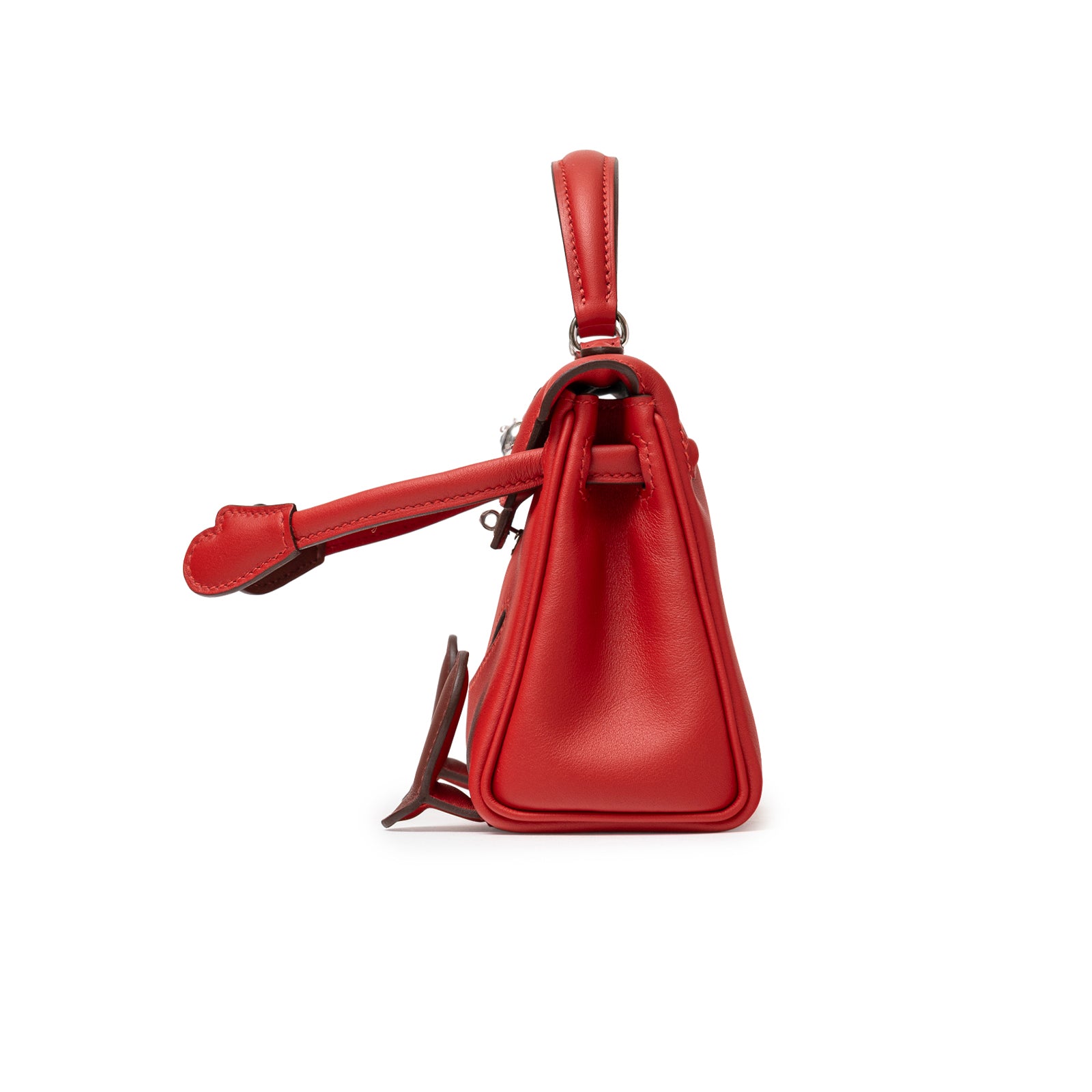 Side view of Hermès Quelle Idolle Kelly Doll Rouge Radieux Rouge H Swift Palladium Hardware handbag showing smooth leather and handle detail.
