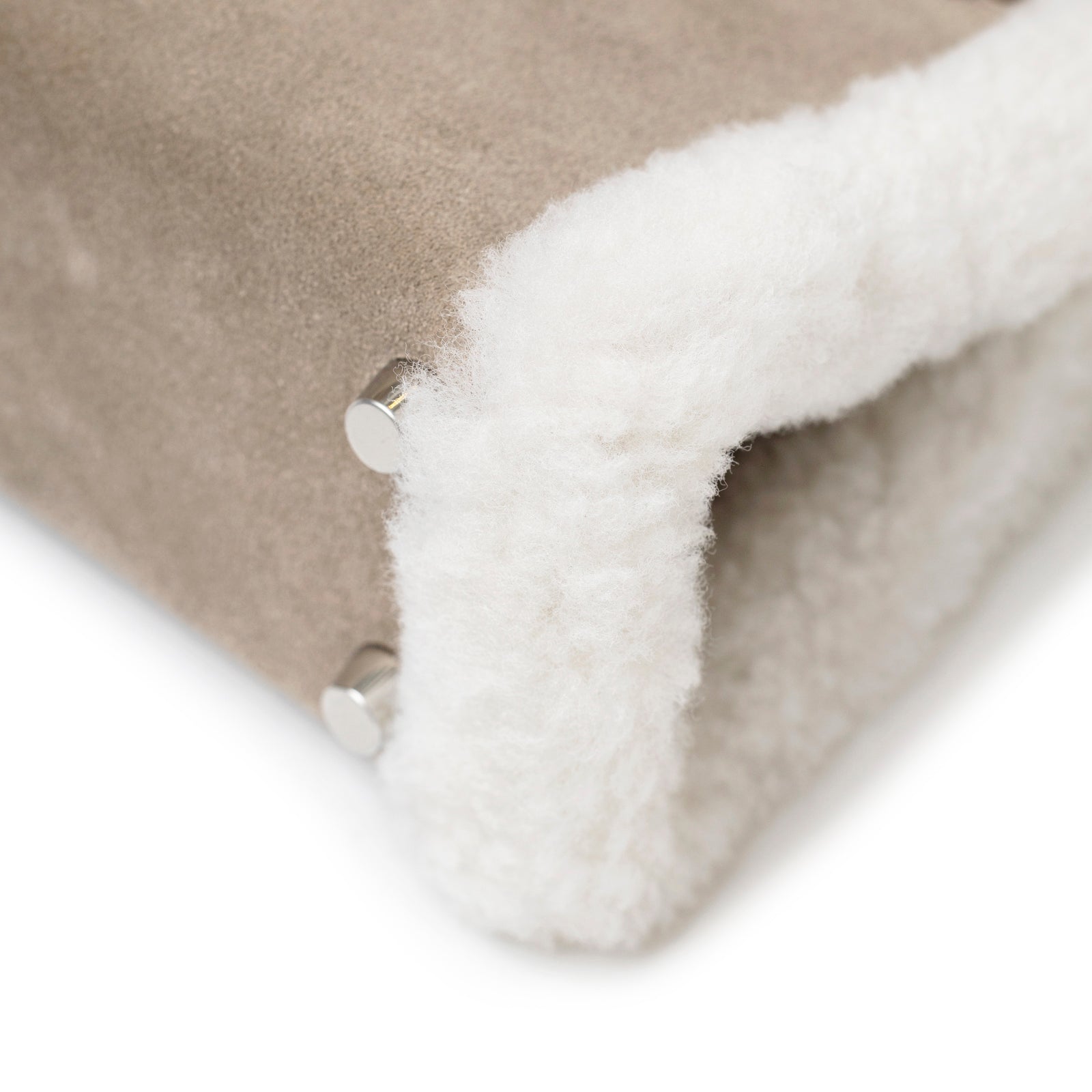 Close-up of Hermès Teddy Mini Kelly II Gris Caillou Etoupe Grizzly Swift Palladium Hardware corner with soft shearling trim detail.
