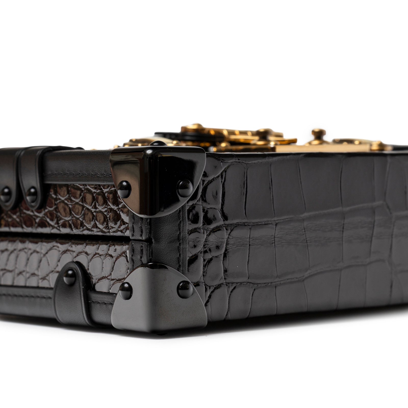 Close-up angled view of Louis Vuitton Petite Malle Black Shiny Niloticus Gold Hardware showing corner detail and croc texture