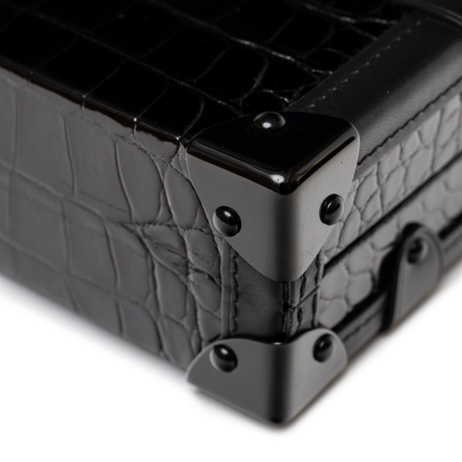 Close-up of Louis Vuitton Petite Malle Black Shiny Niloticus Gold Hardware showing croc texture and black corner details